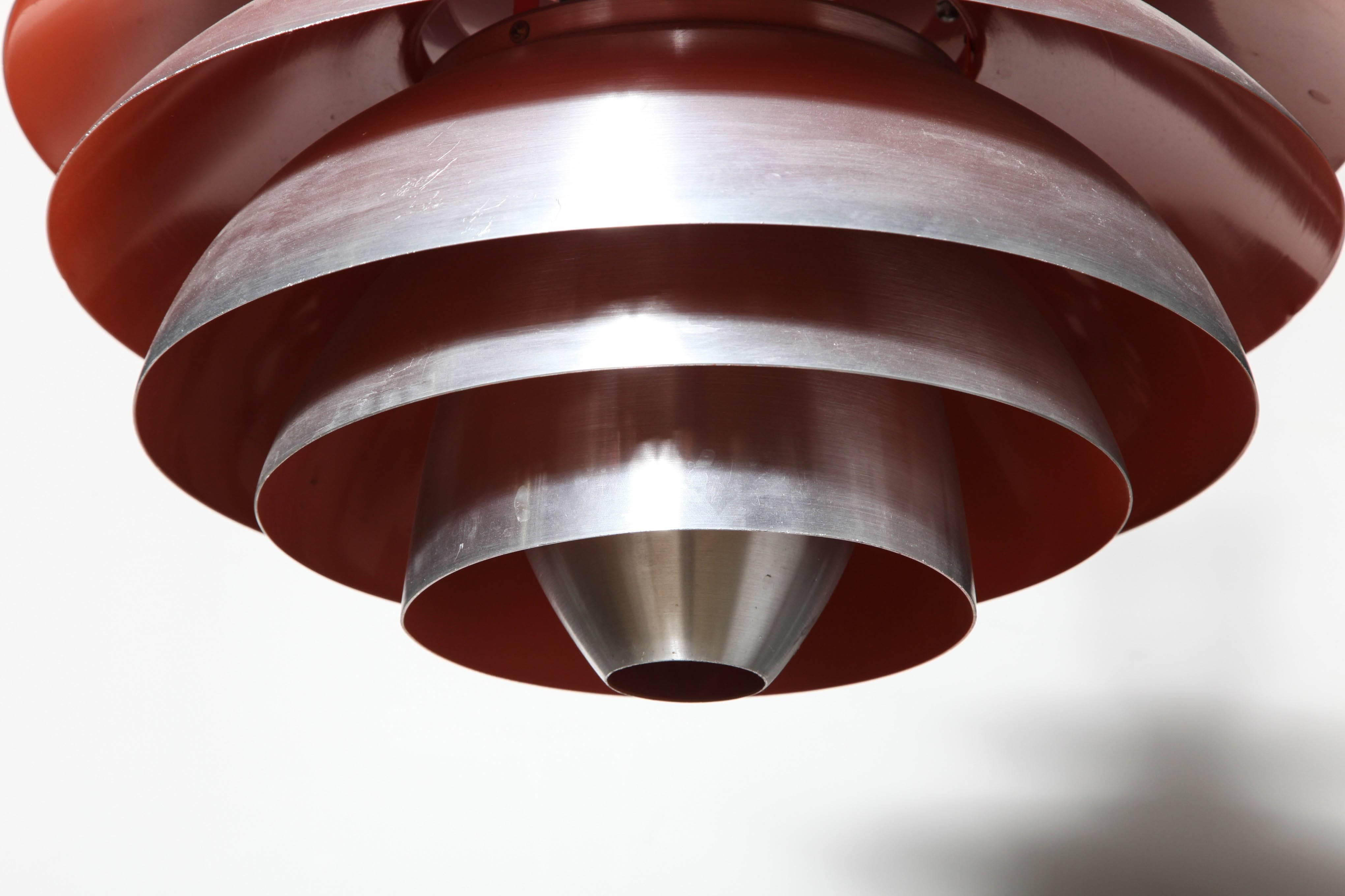 Danish Modern Poul Henningsen for Louis Poulsen PH Louvre Brushed Aluminum Hanging Lamp. Featuring an oval form with nine reflective Brushed Aluminum concentric bands and Warm Red toned Orange enameled interior. Complimentary warm light.  Adjustable