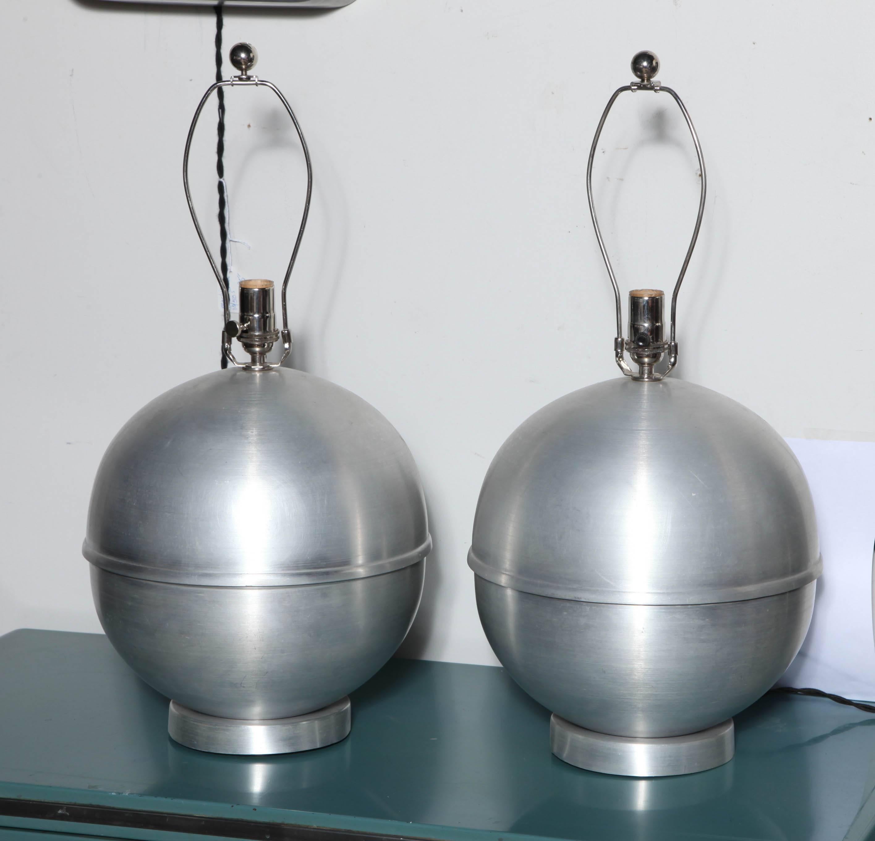 Modernist pair of Russel Wright Style All Spun Aluminum Table Lamps. Featuring a Globe form with center banded detail on round 6D Spun Aluminum base. Lampshades shown for display only. Lightly restored. Rewired with new Nickel plated hardware and