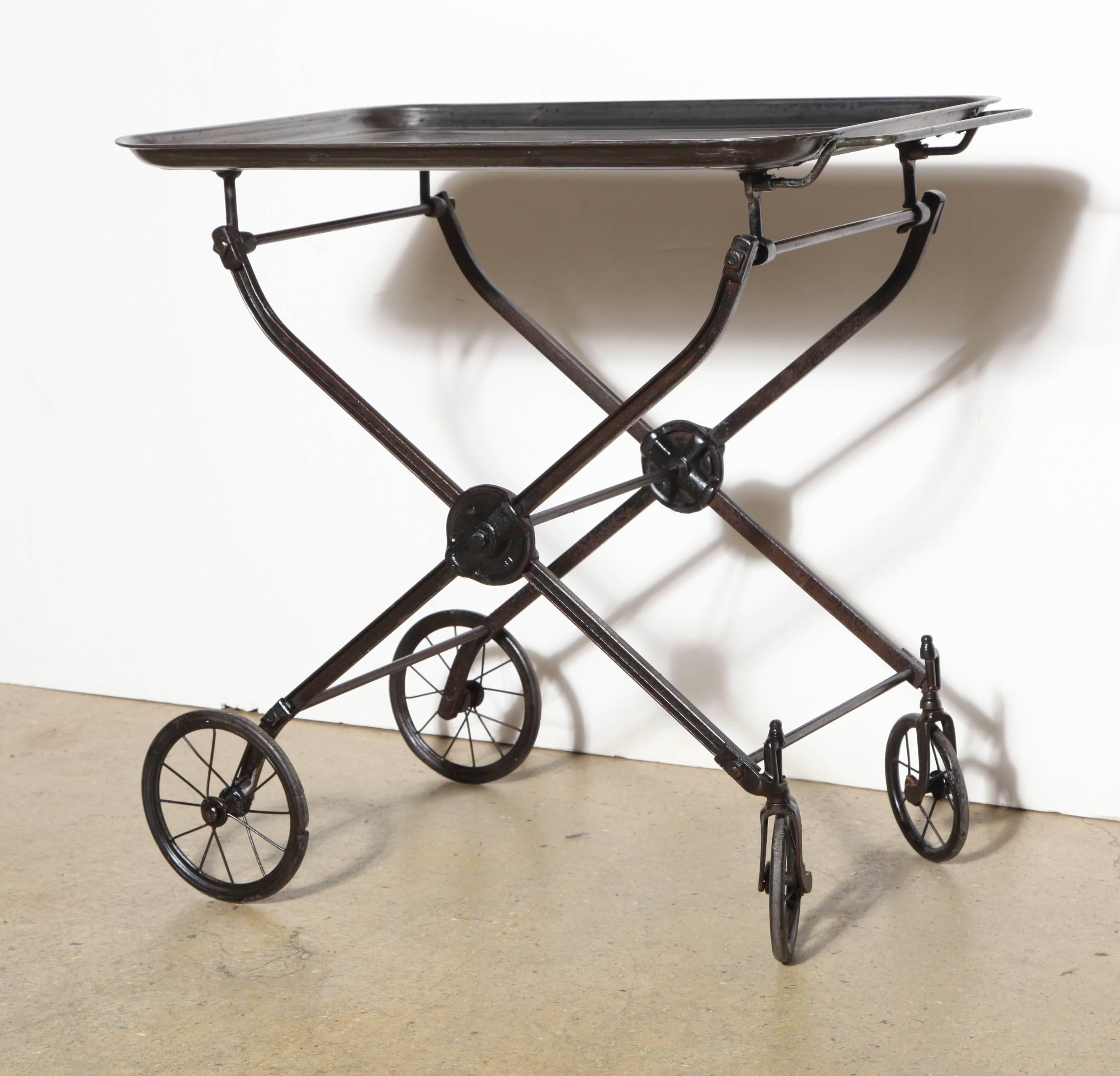 Edwardian Rolling and Folding Black Iron Hotel Beverage Trolley, Occasional Serving Cart, Dry Bar. Featuring Iron casting with spoked wheel detail. Larger lipped tray with handle. Folds for storage. Industrial. Sturdy. Fine design. Versatile.