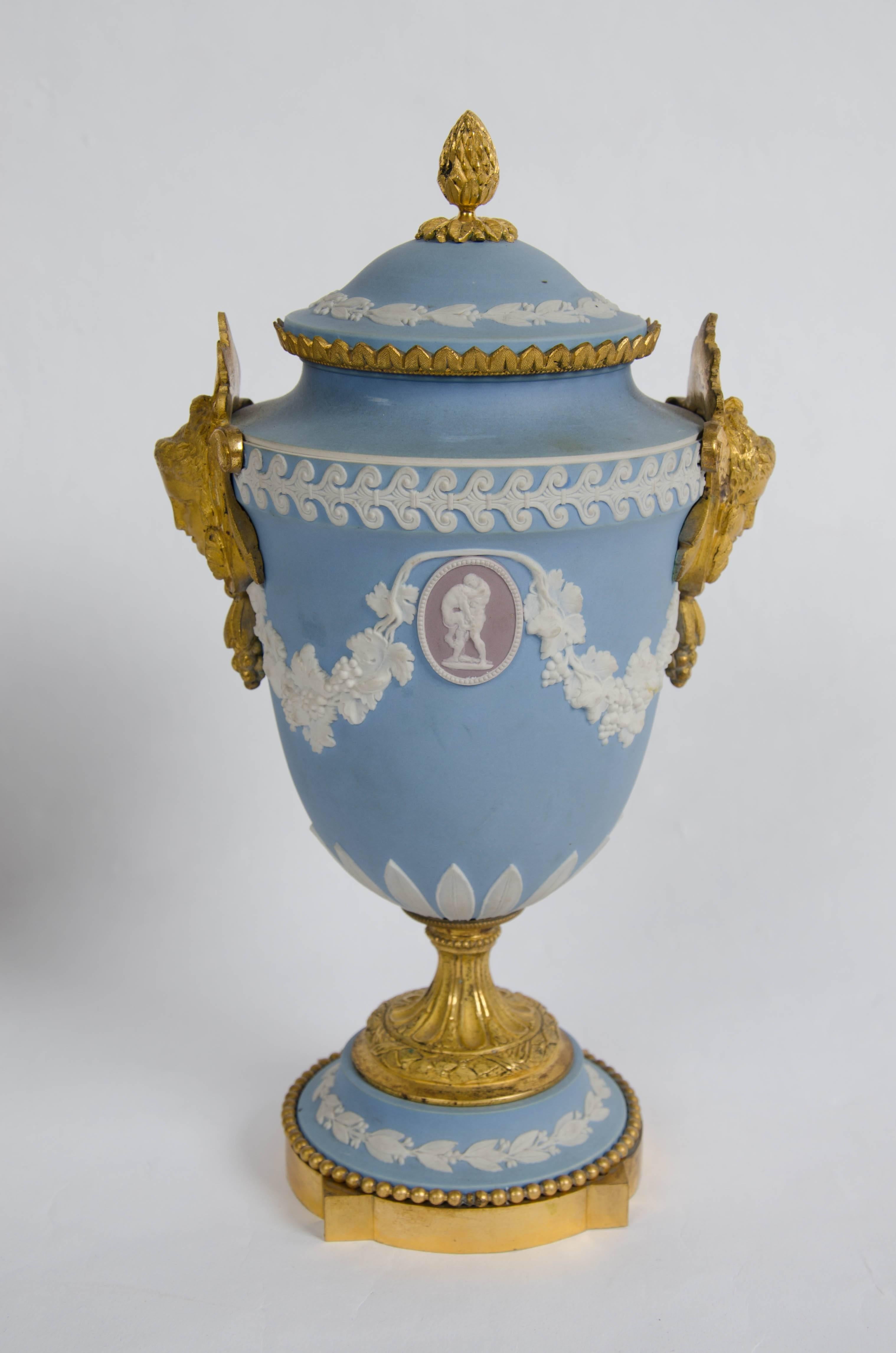 
A good quality pair of Wedgwood Jasper, Tri-colour urns and covers.
The blue ground applied with lavender ground medallions of classical figures, pendant from fruiting vine swags, above a stiff leaf band, the sides applied with two ormolu