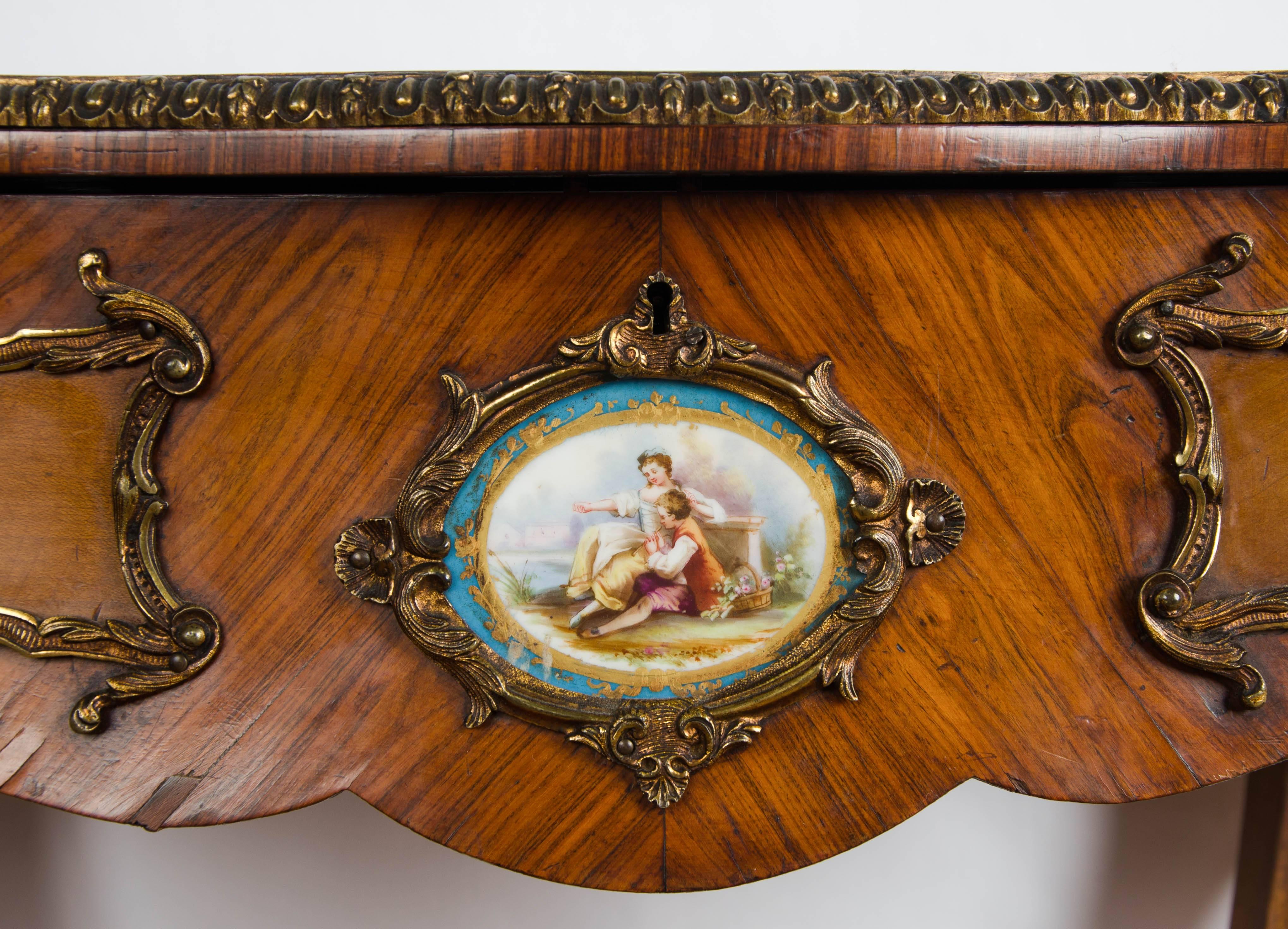 Table d'appoint en marqueterie de bois de roi de style Louis XV, de très bonne qualité, avec des plaques de porcelaine de Sèvres insérées dans la frise, des montures en bronze doré et reposant sur des pieds cabriole. Les charnières de la partie