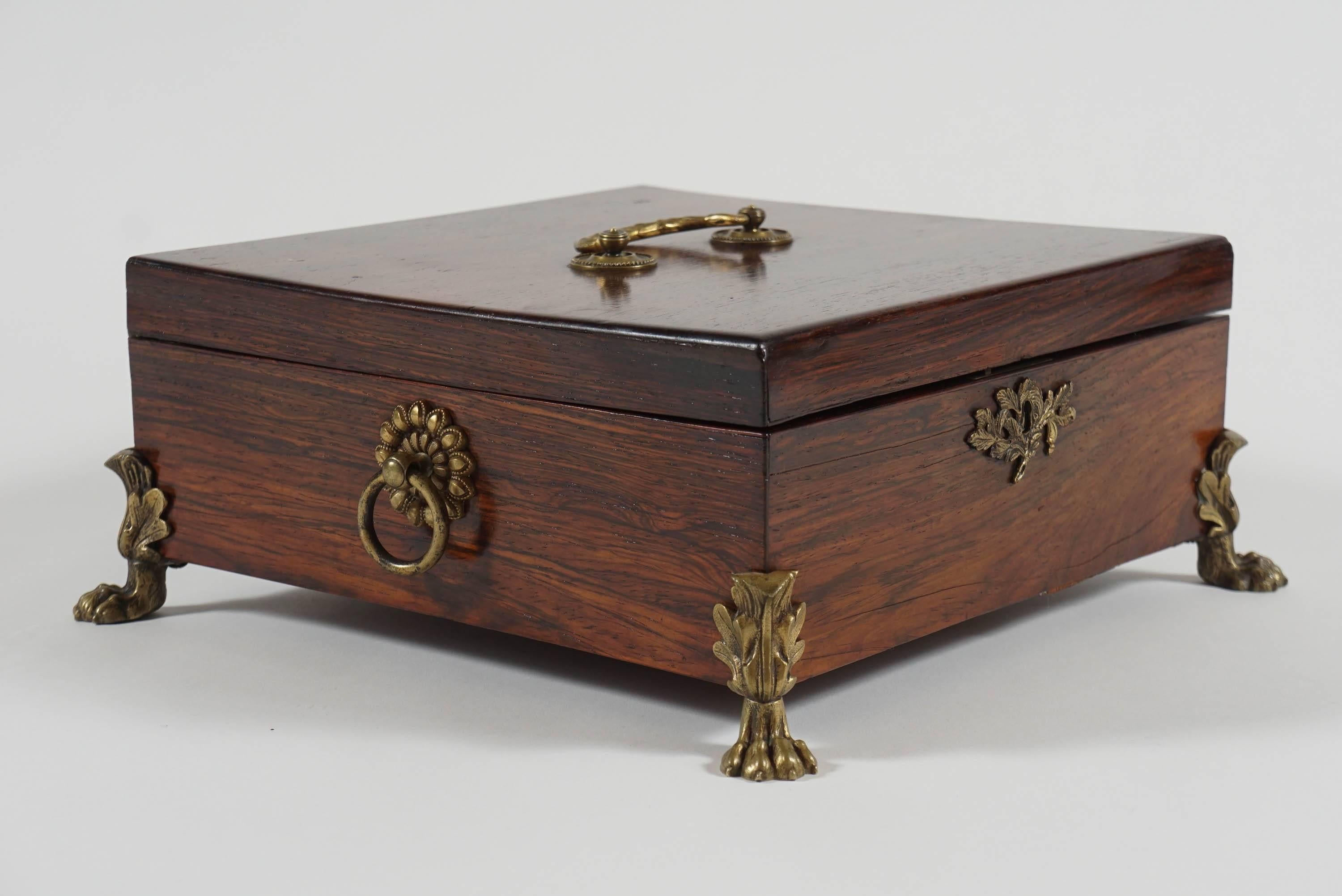 Elegant George III, English Regency period, circa 1810, rosewood dresser or jewelry box having original finely cast bronze hardware of top bail handle, key escutcheon, side ring-handles, and four corner lion-paw form feet with acanthus foliate tops,