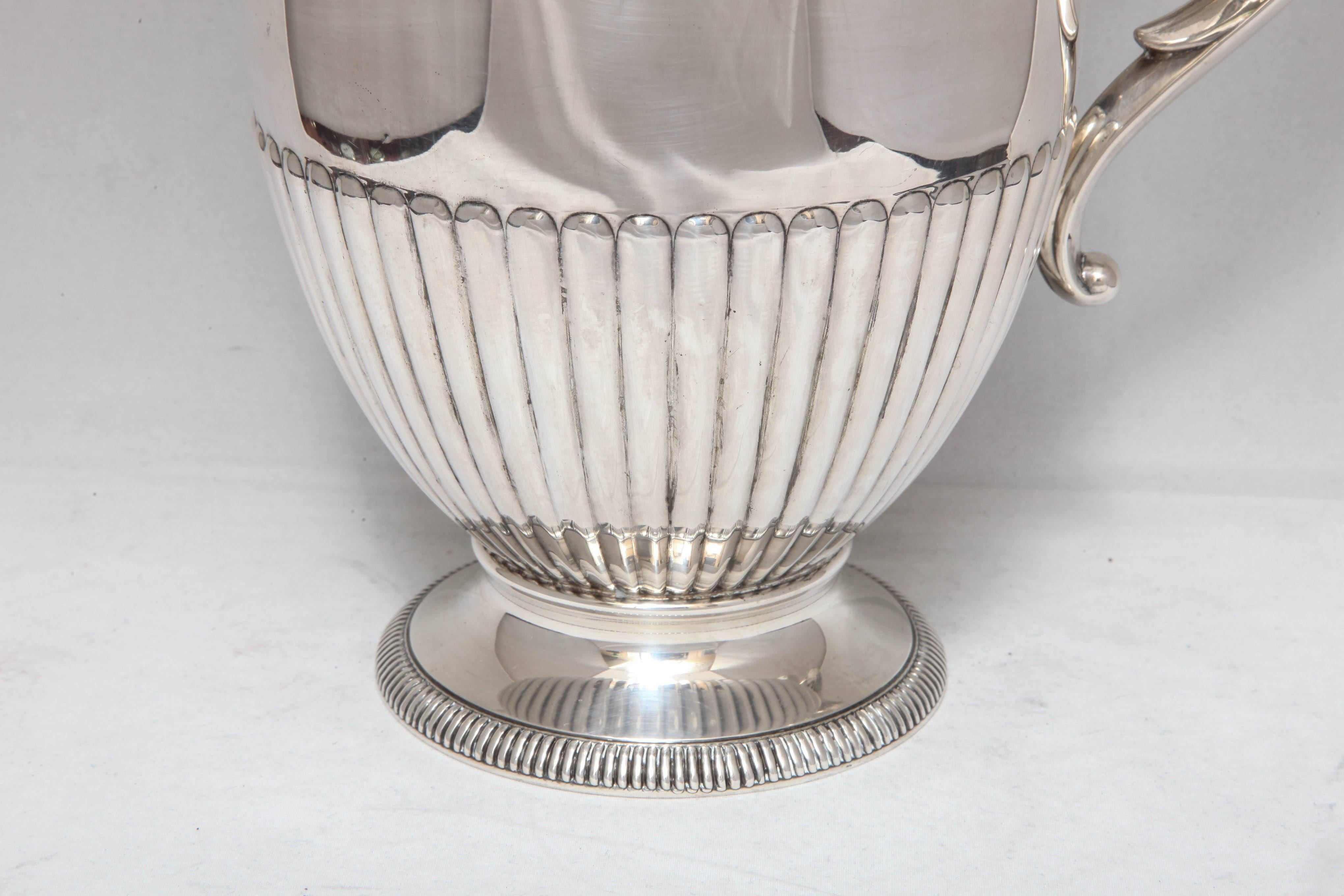 Art Deco, sterling silver water pitcher, Fisher Silversmiths, Inc., New Jersey, circa 1930s. Baluster base. Fluted design is picked up on edge of base. Measures: 10