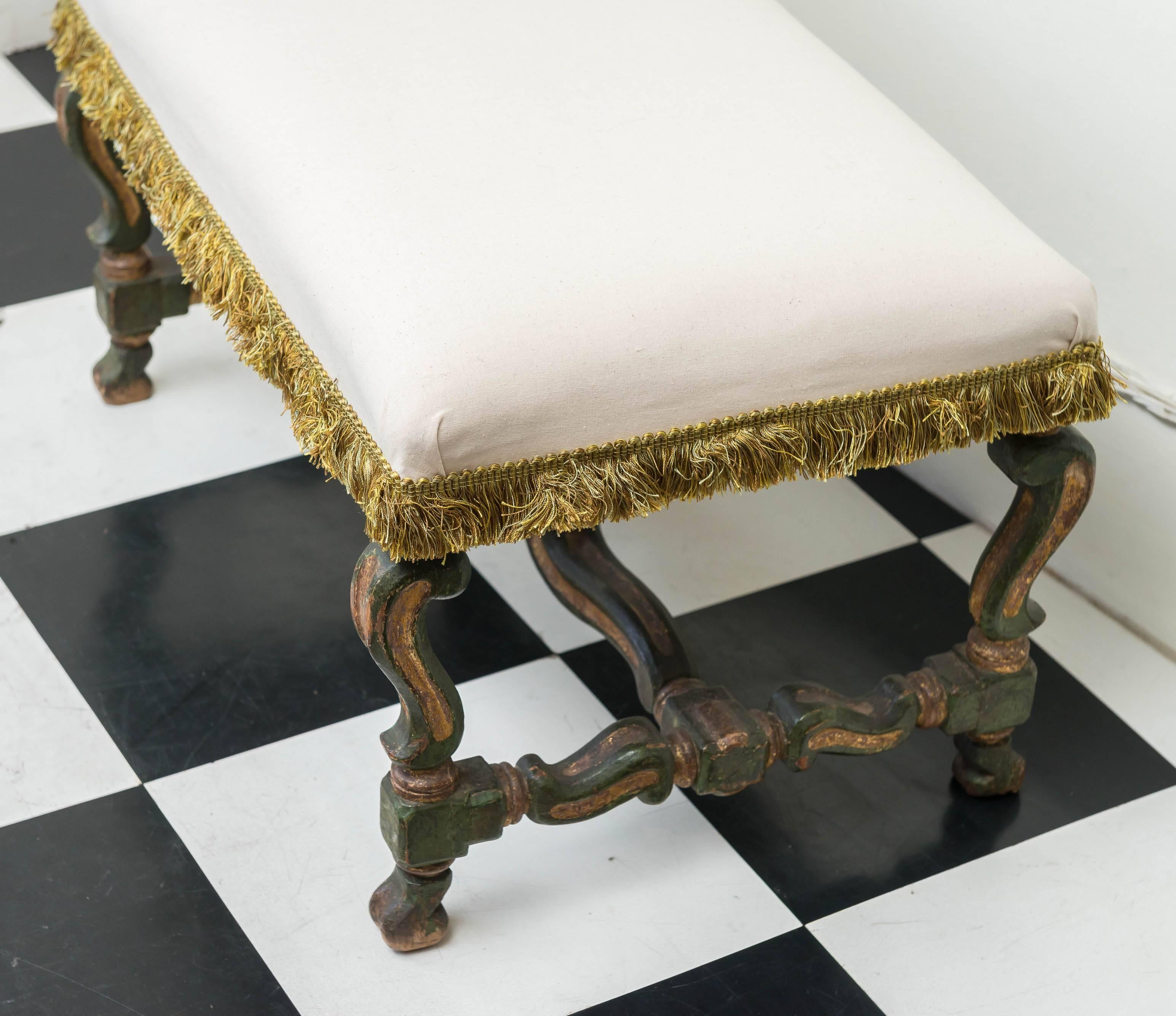17th century Italian parcel-gilt and green painted bench. Retains the original surface with wear and subtle craclure. Covered in a simple cream muslin with an old green fringe. Scroll form legs and stretchers.