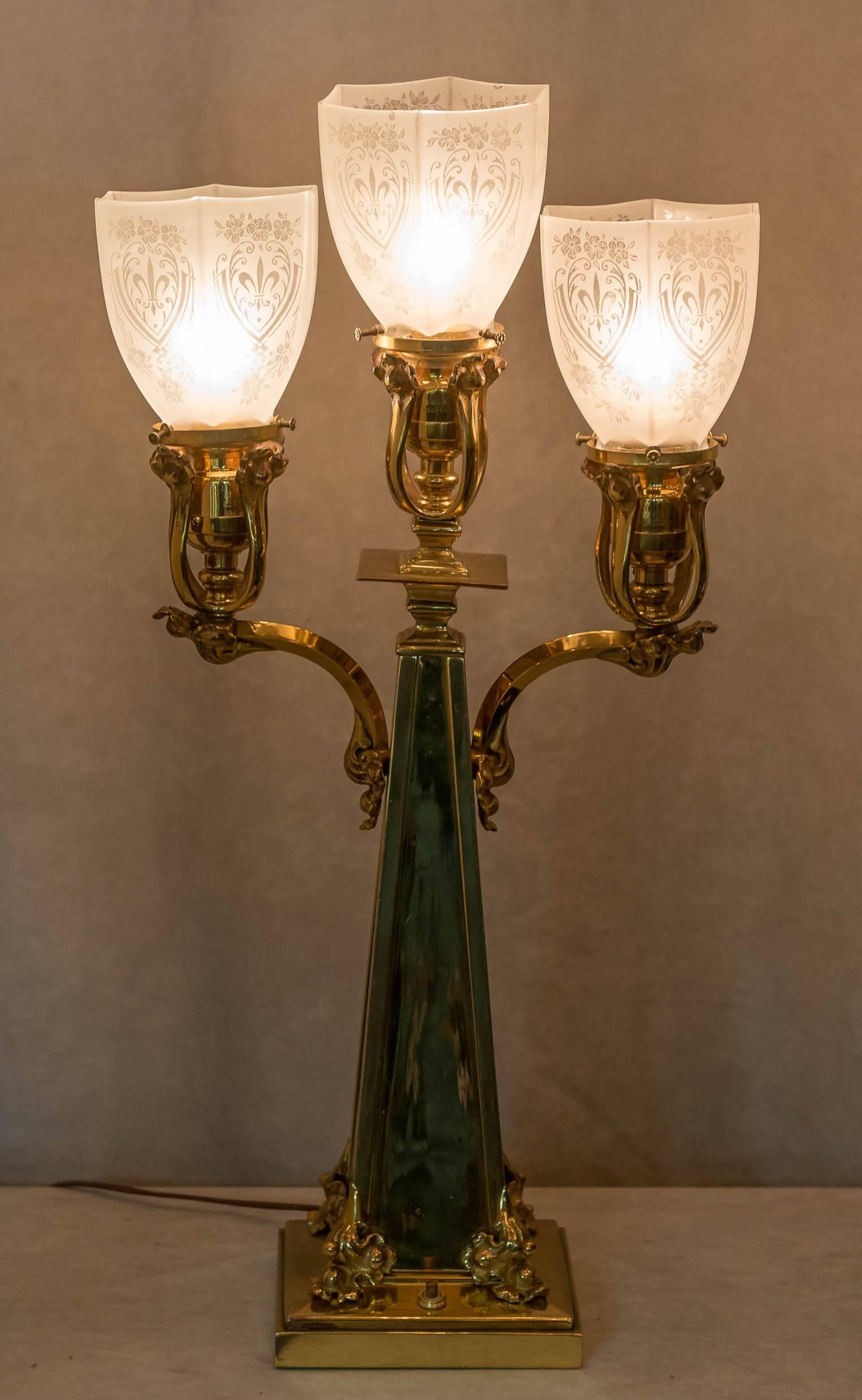 A most unusual three-arm table lamp. All polished bronze with beautiful cast bronze shade holders, and very attractive period stencil etched glass shades. A really handsome package that will decorate, and offer plenty of good light. We bought it