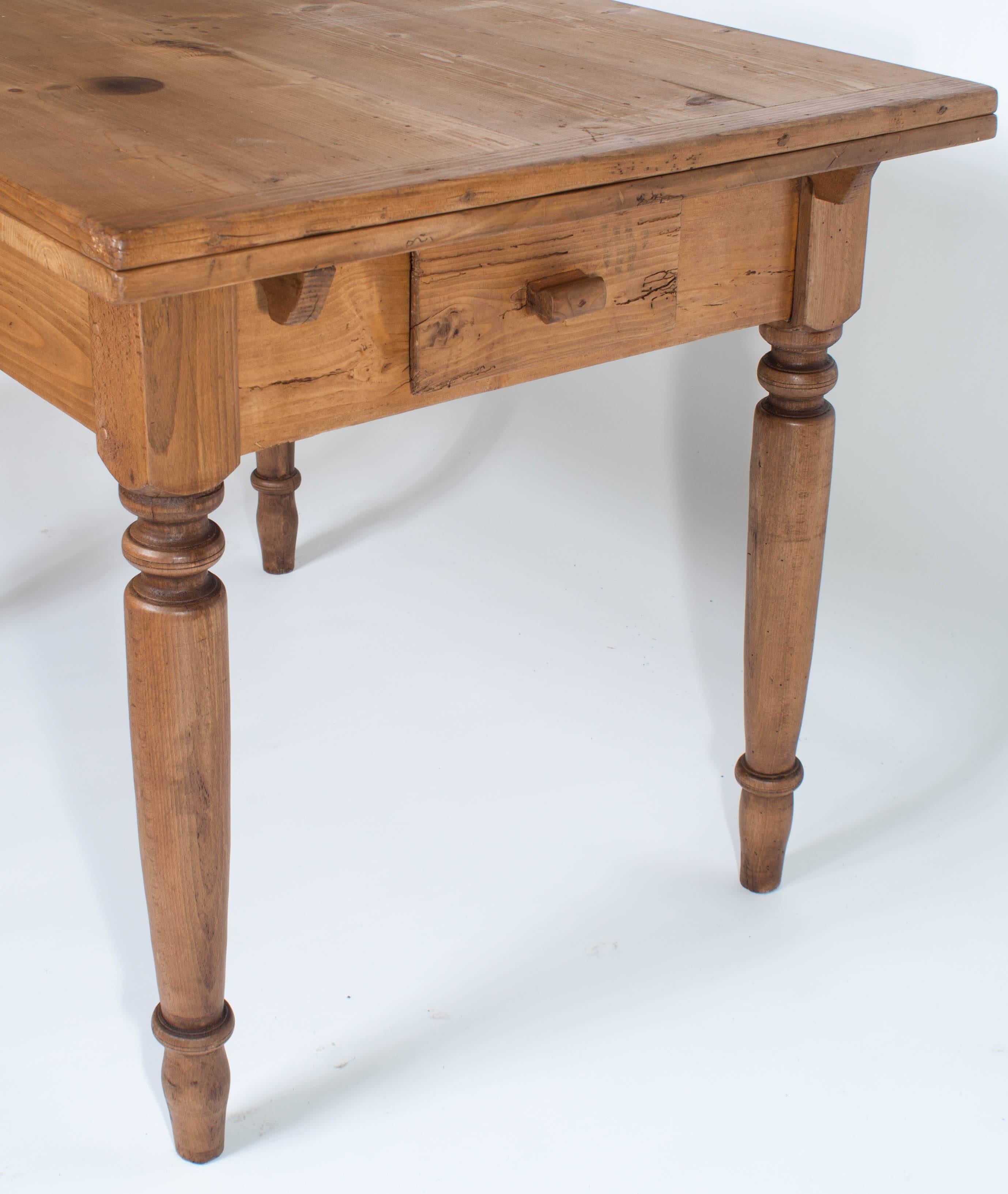 A handsome and versatile pine table on four turned beechwood legs, each end having a self storing 18