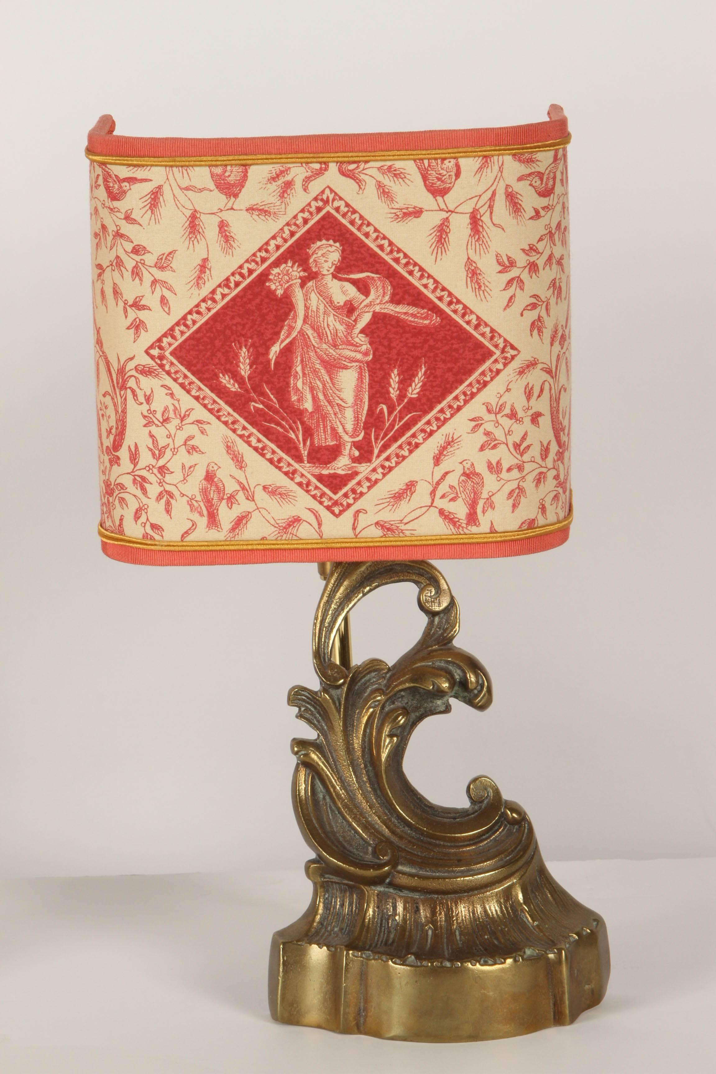 A pair of new electric lamps made from 19th Century andirons. The andirons are in an upswept shape, much like a rising ocean wave. Each of the andirons is topped by a three-sided shade that depicts a classical Greek goddess type of female figure and