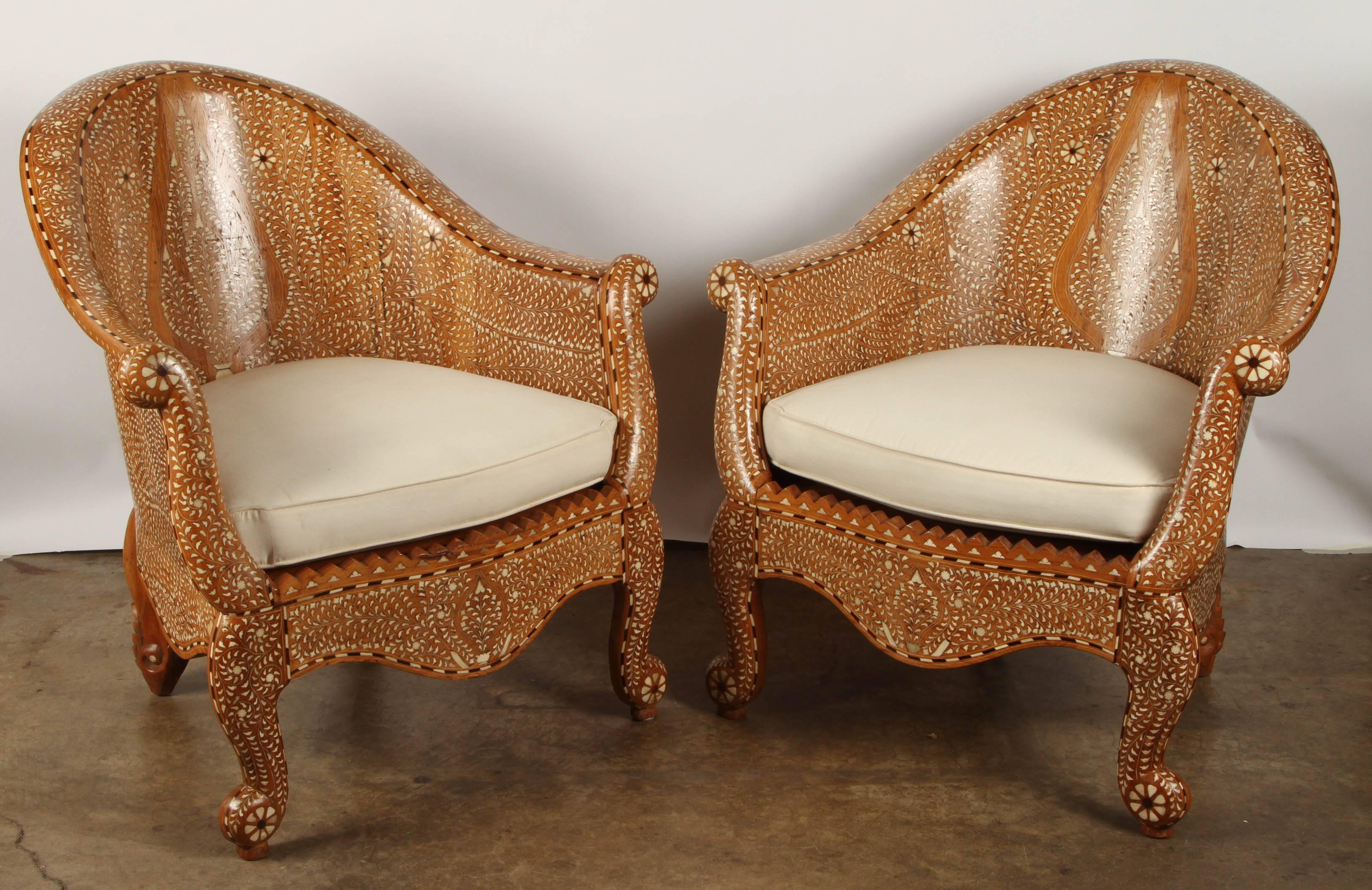 This armchair is made in teak with bone, and is heavily inlaid with depictions of cypress trees and swirls of leaves and/or petals. The back of the chair sweeps gracefully into the arms in a single piece, and ends in a flower shape.