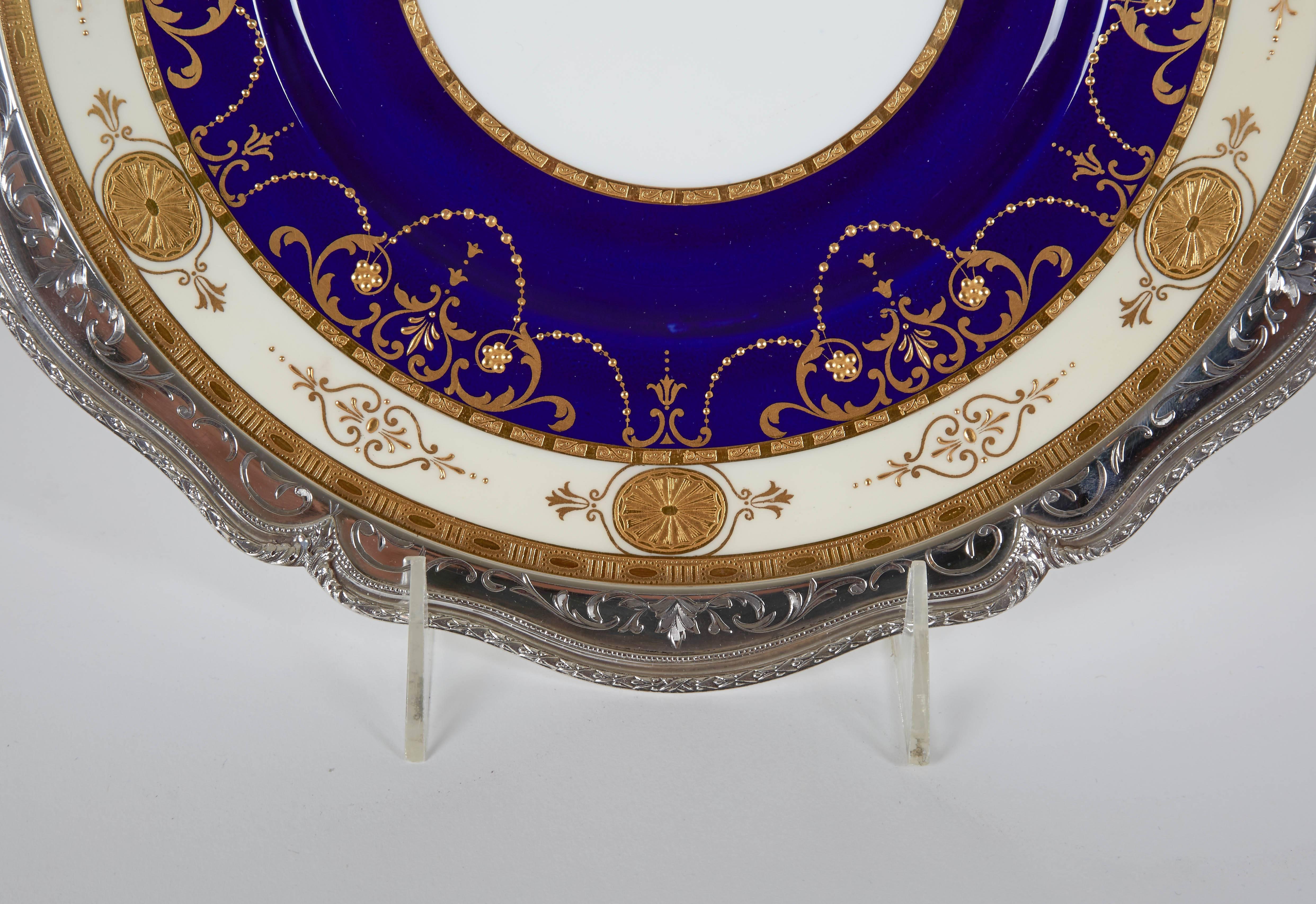 Set of eight rare porcelain plates with raised gold jeweled beading with medallion accents. A hand chased sterling collar crafted by Shreve & Co. Sterling enhances these presentation plates. Shreve hallmark confirms the date of 1900. All gilt design