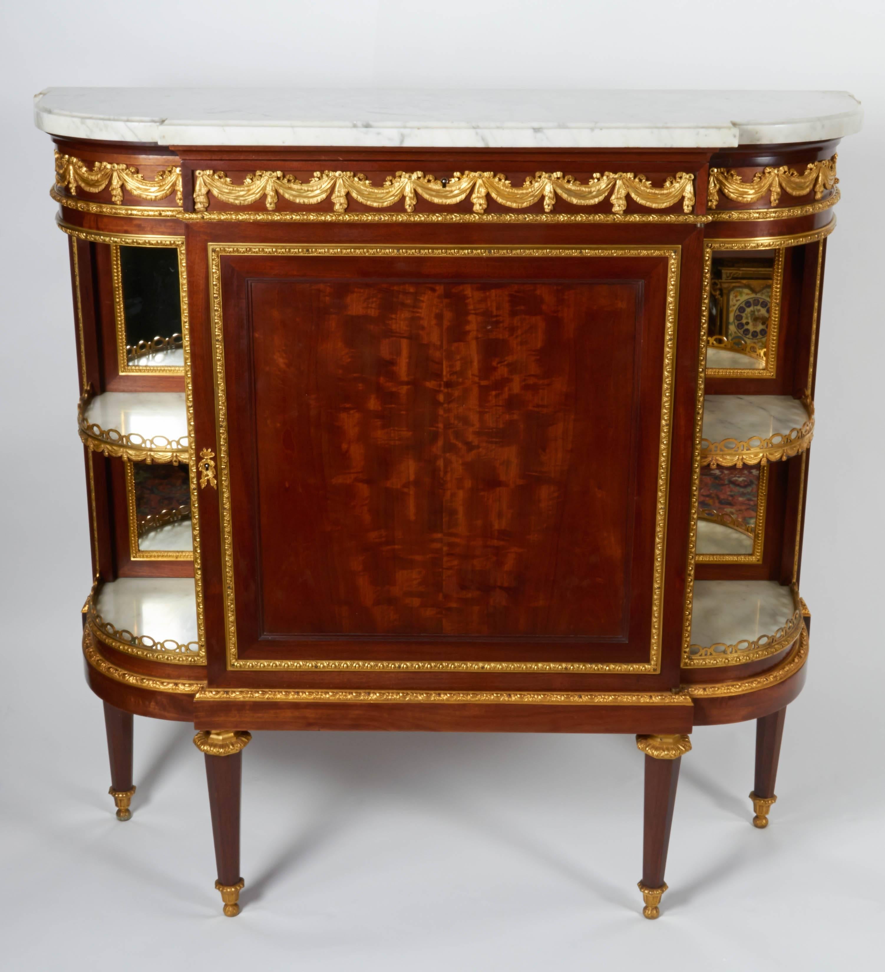 A fine pair of antique French Louis XVI style, ormolu-mounted mahogany side cabinets each having double sided, original beveled mirrored back display corners on either side. The ormolu all finely casted and hand chiseled with original mercury