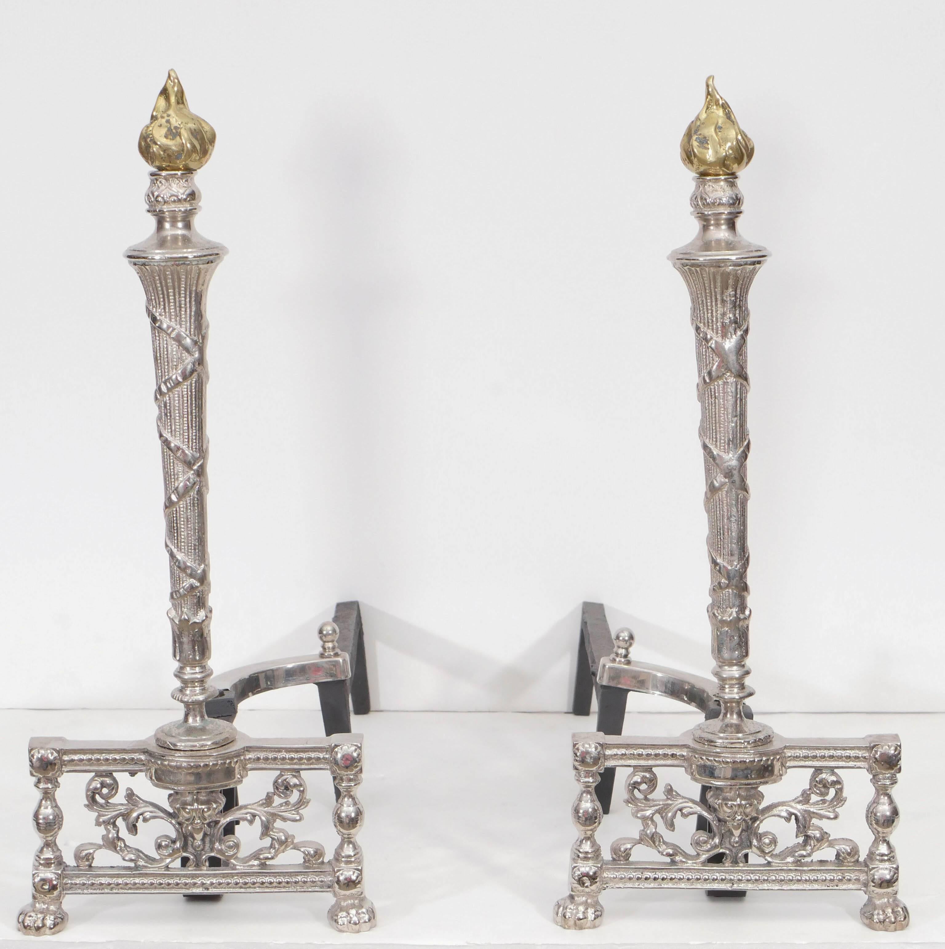 Pair of Art Deco polished nickel andirons with a stylized brass flame finials and cast iron backs.