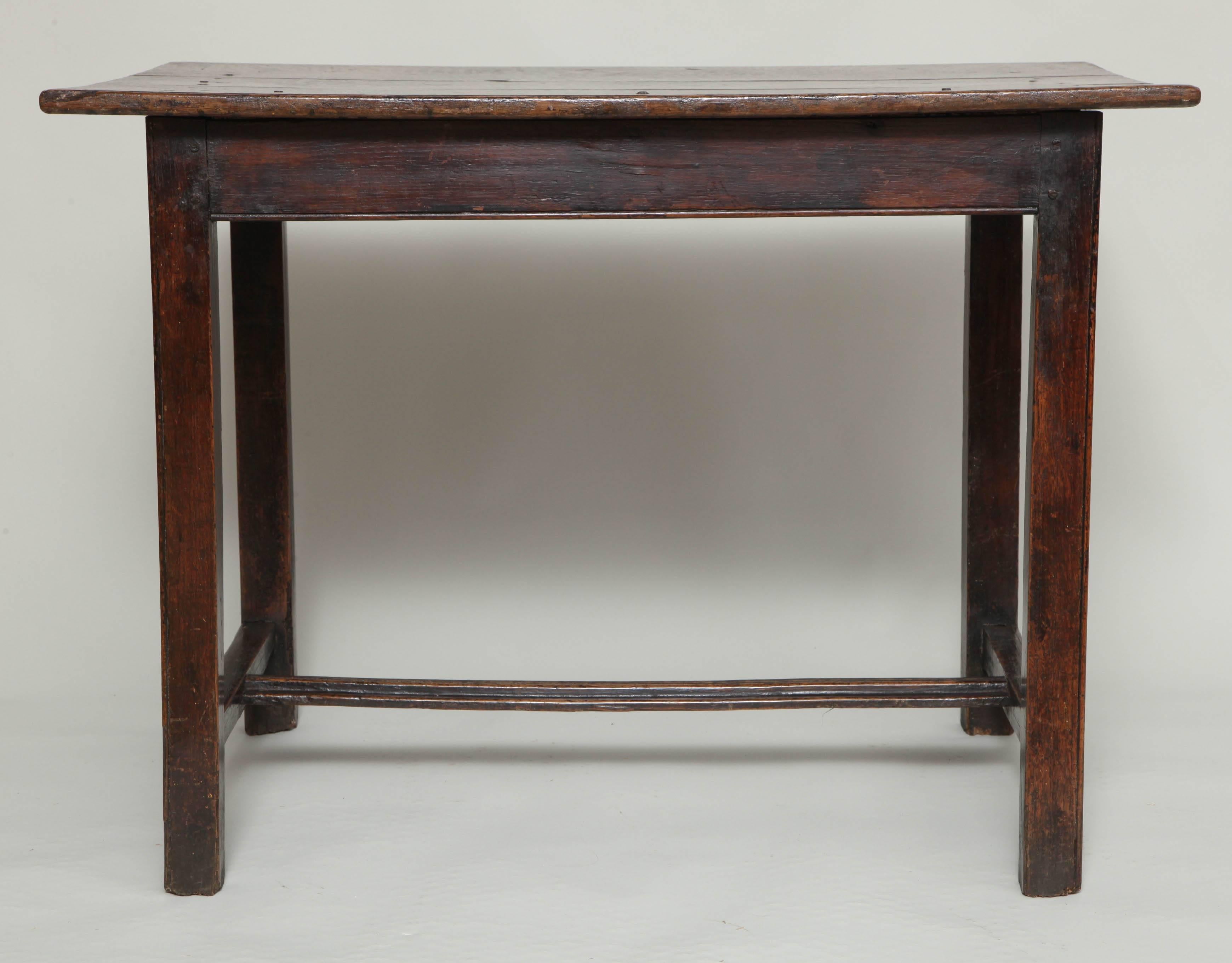 A late 18th century English oak center table having two-piece top over beaded straight legs joined by molded H-stretcher. Good mottled color.
