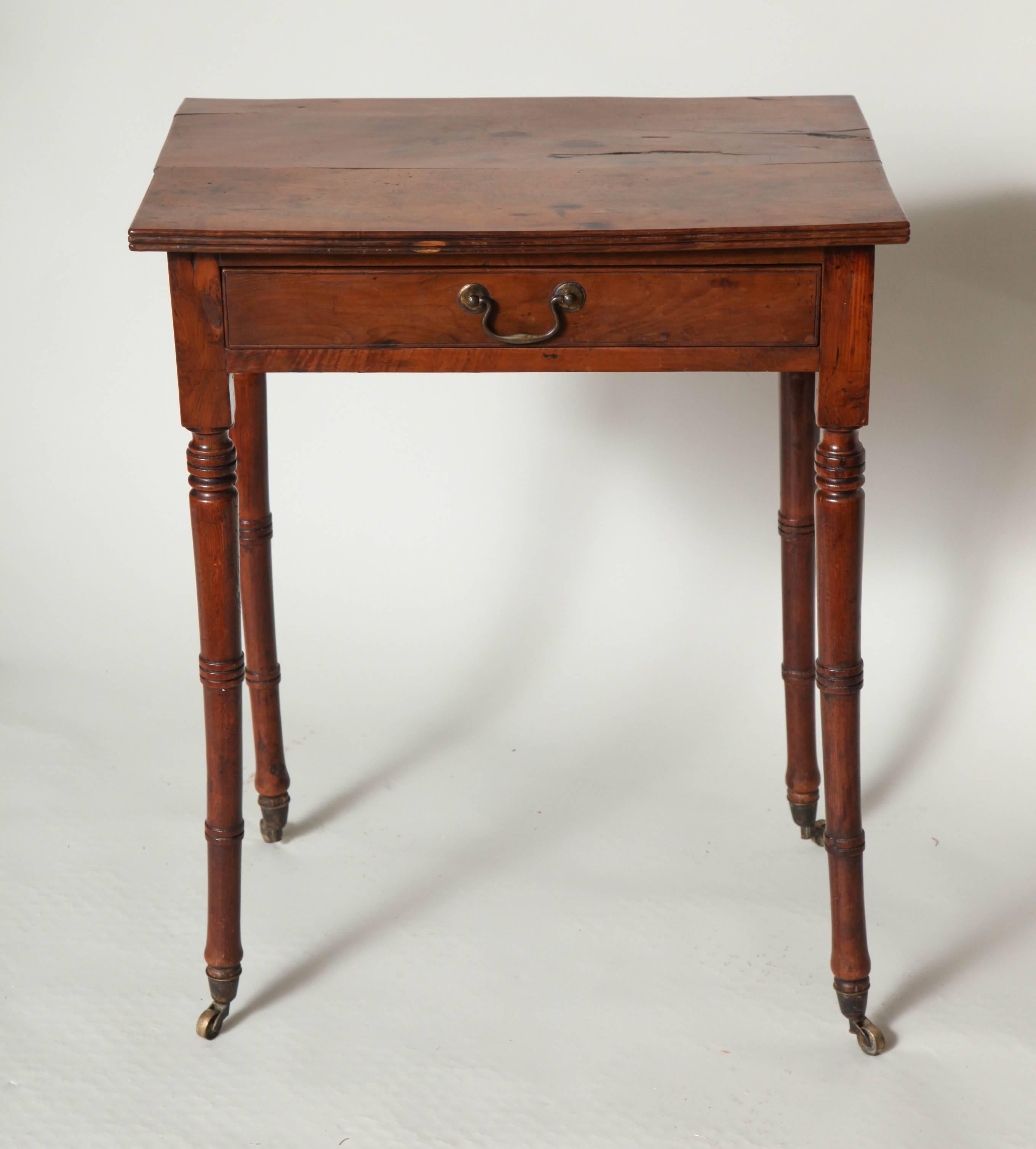 Fine George III yew wood side table, the two plank top with ribbed edge, the single drawer with original swan neck pulls, standing on ring turned tapered legs ending in original brass casters, the legs all slightly out-swept, probably due to the