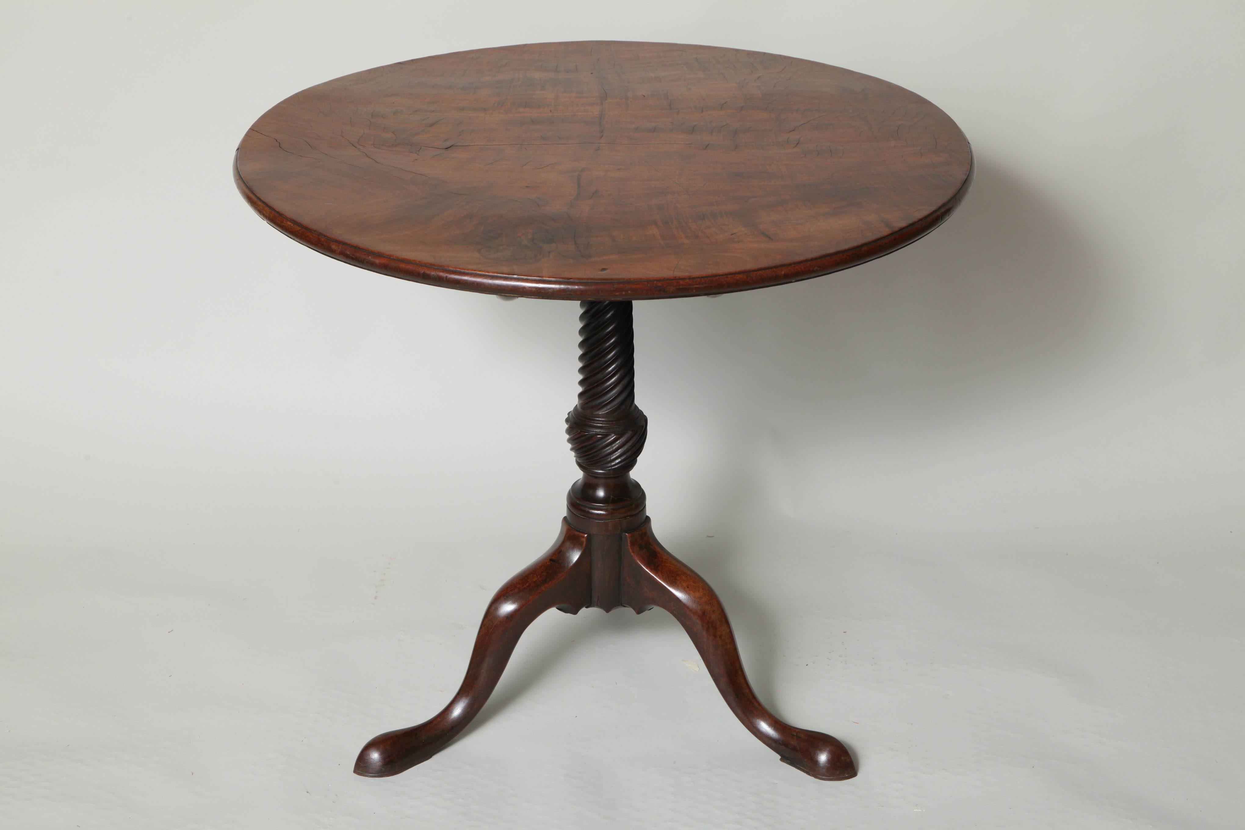 A very fine George III mahogany tripod tea table, the exceptionally well figured top with turned molded edge over spiral fluted turned shaft, the cabriole legs ending in slipper feet.
The top of this table is remarkable for several reasons: First