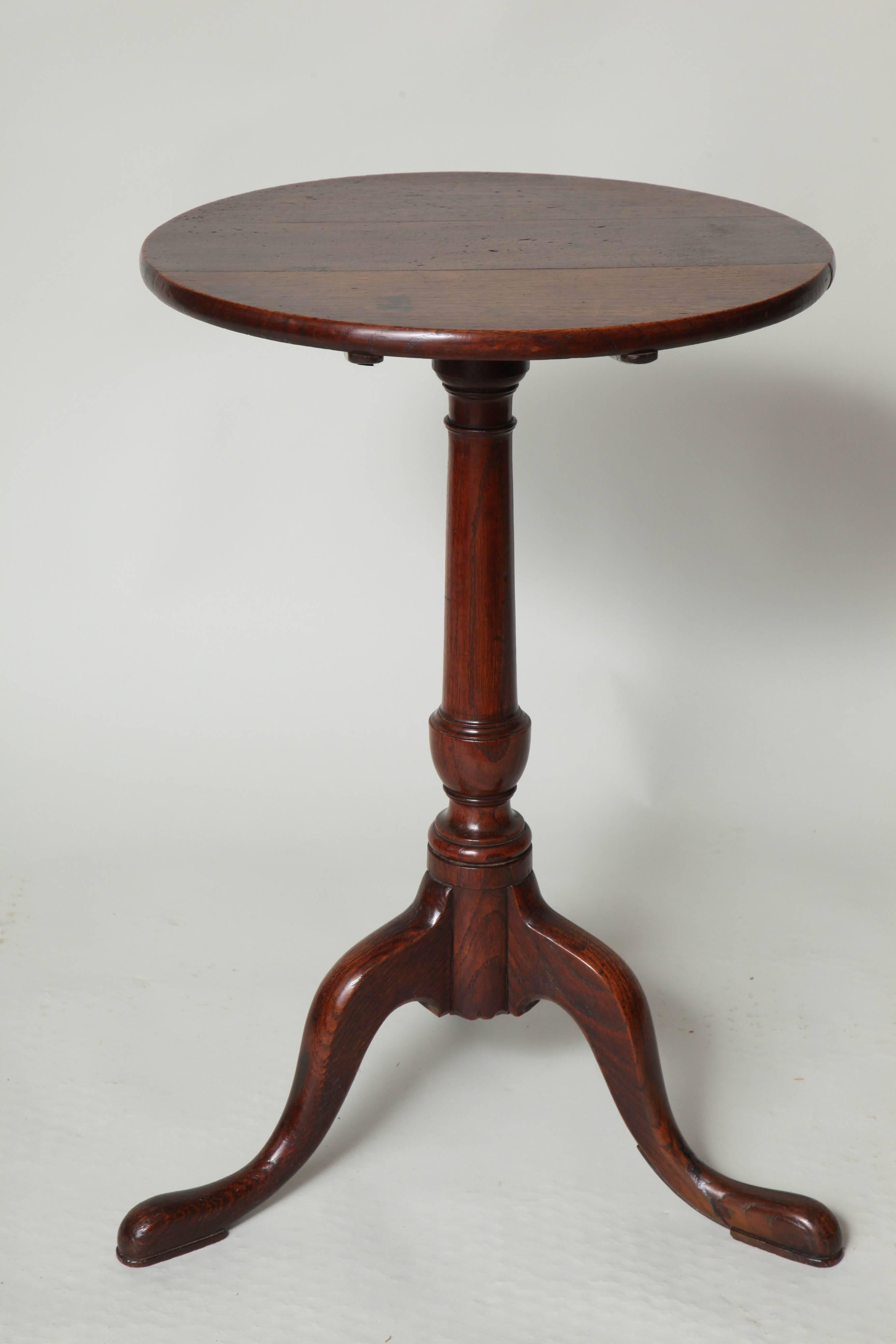 An 18th century English oak tilt-top tripod win table or candle Stand, the turned circular top over a balustrade shaft, standing on three well-formed legs, the whole with pleasing color.
