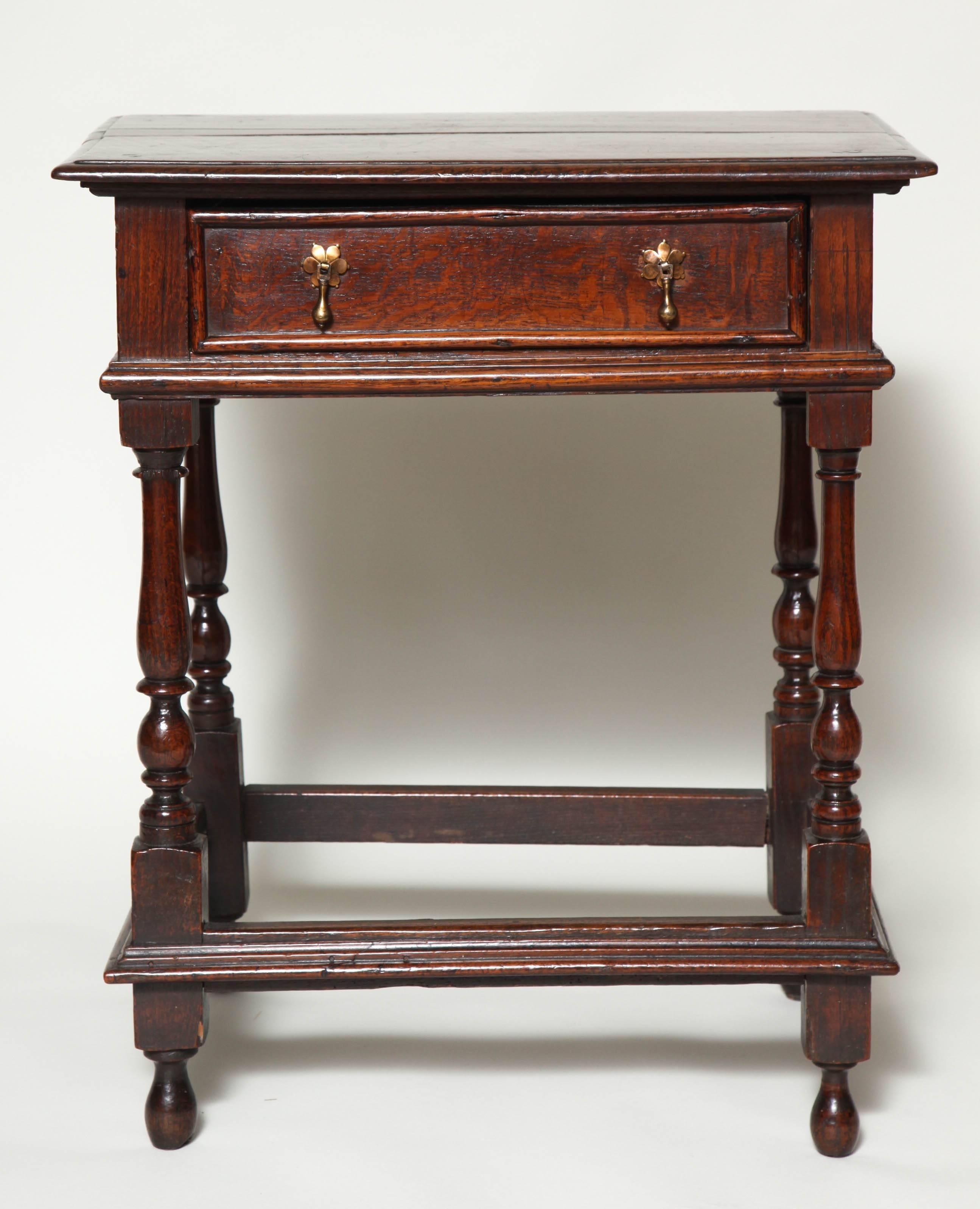 Late 17th century English oak side table with molded top over single molded front drawer with double tear drop pulls on boldly turned baluster legs joined by rare molded box stretcher and standing tall on original elongated bun feet. Nice