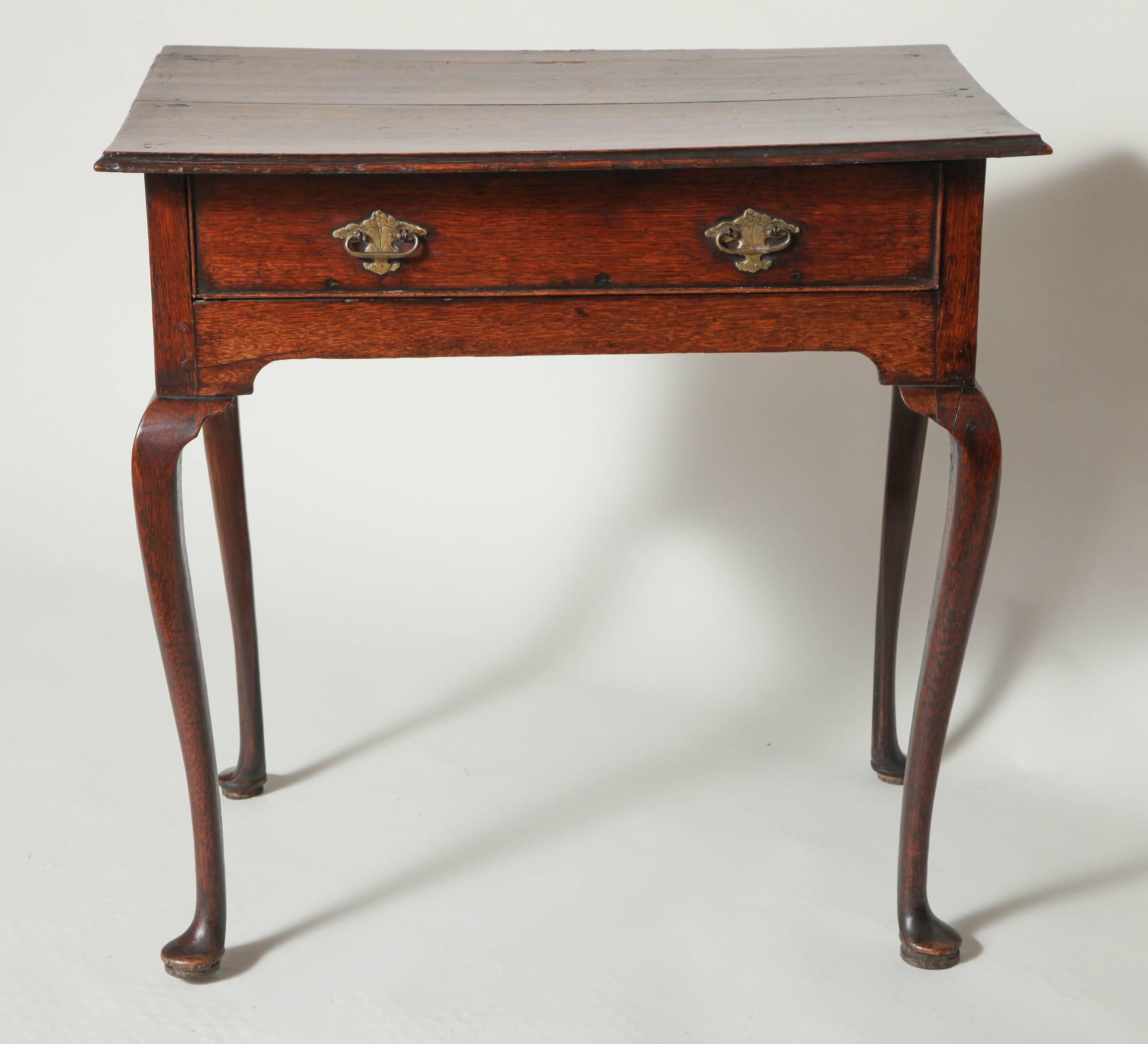 Graceful 18th century English oak Queen Anne table, with ogee molded top over single drawer retaining original etched brass hardware, over shaped apron and standing on elegant cabriole legs ending in pad feet, the whole with good rich color and