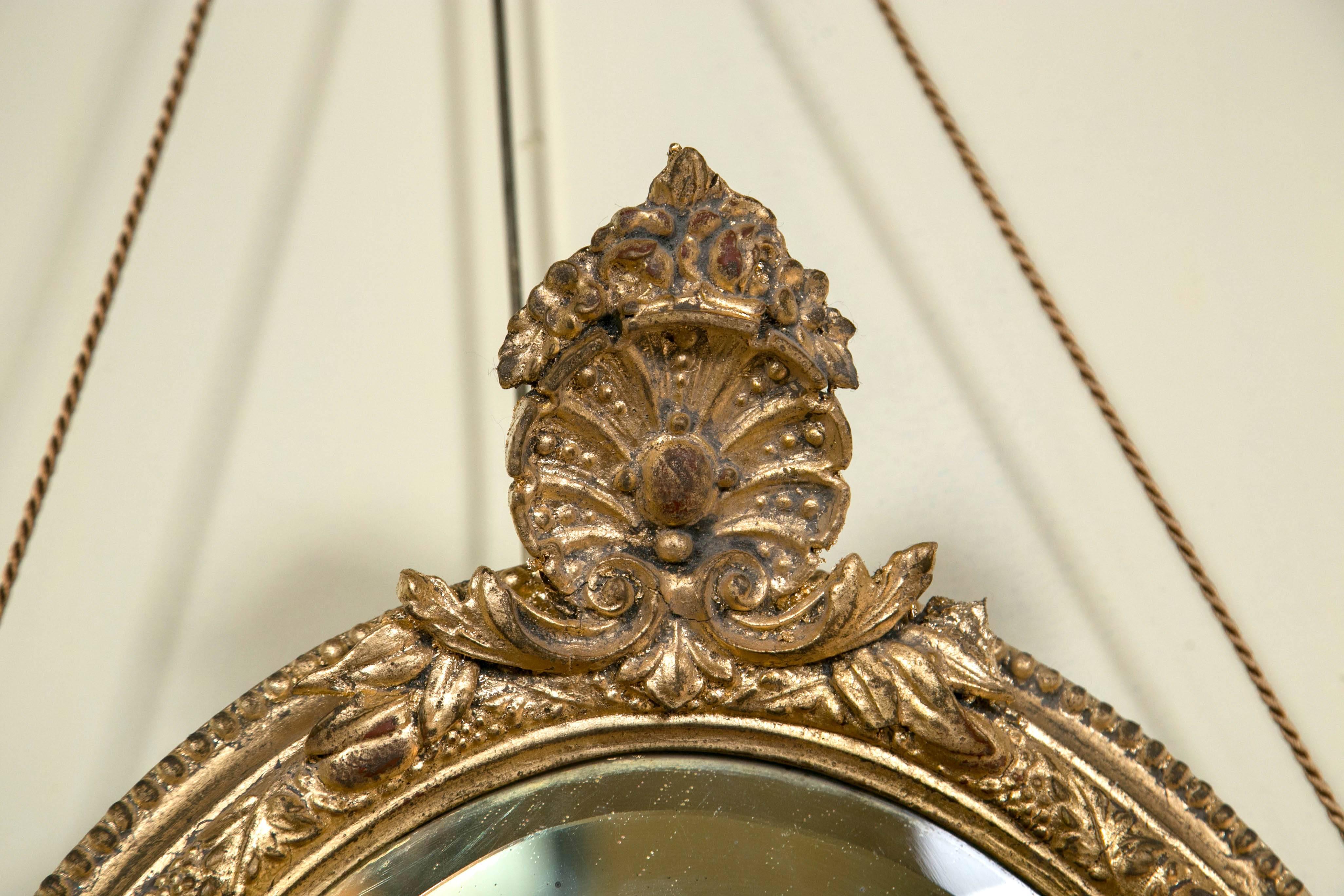 Pair of 19th century mirror oval sconces. Giltwood design with two candle sconces on each individual mirror. Beautifully carved and hung with a thin silk sturdy rope. Leaf and flower carved designs. An exquisite and lovely pair.