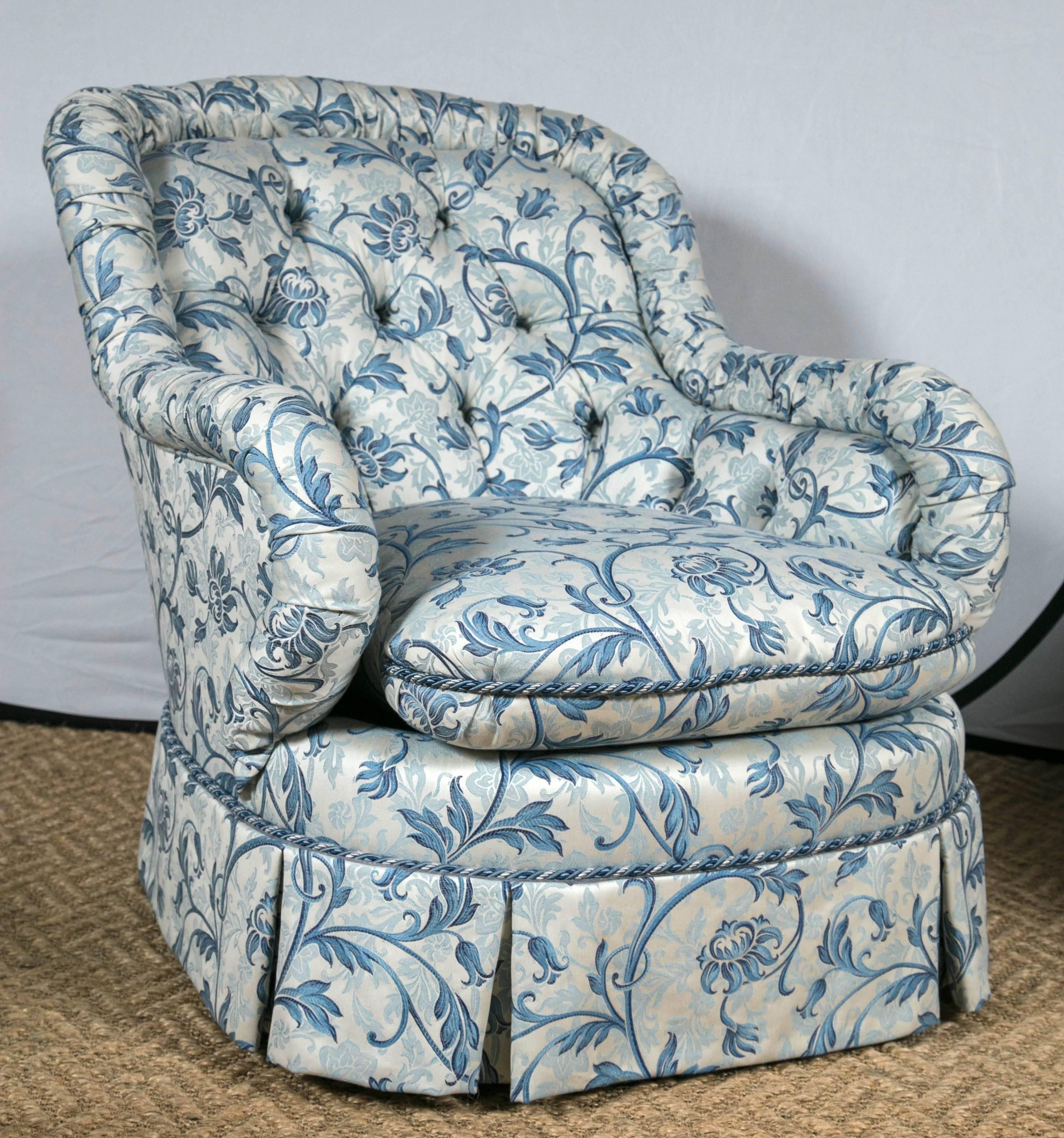 Pair of tufted barrel back chairs. Possibly Baker. Beautifully upholstered in a dove white with swirling poppies in a mixture of soft blues. The back is tufted and the blue and white welting sits atop of the pleated skirt. These are fantastically