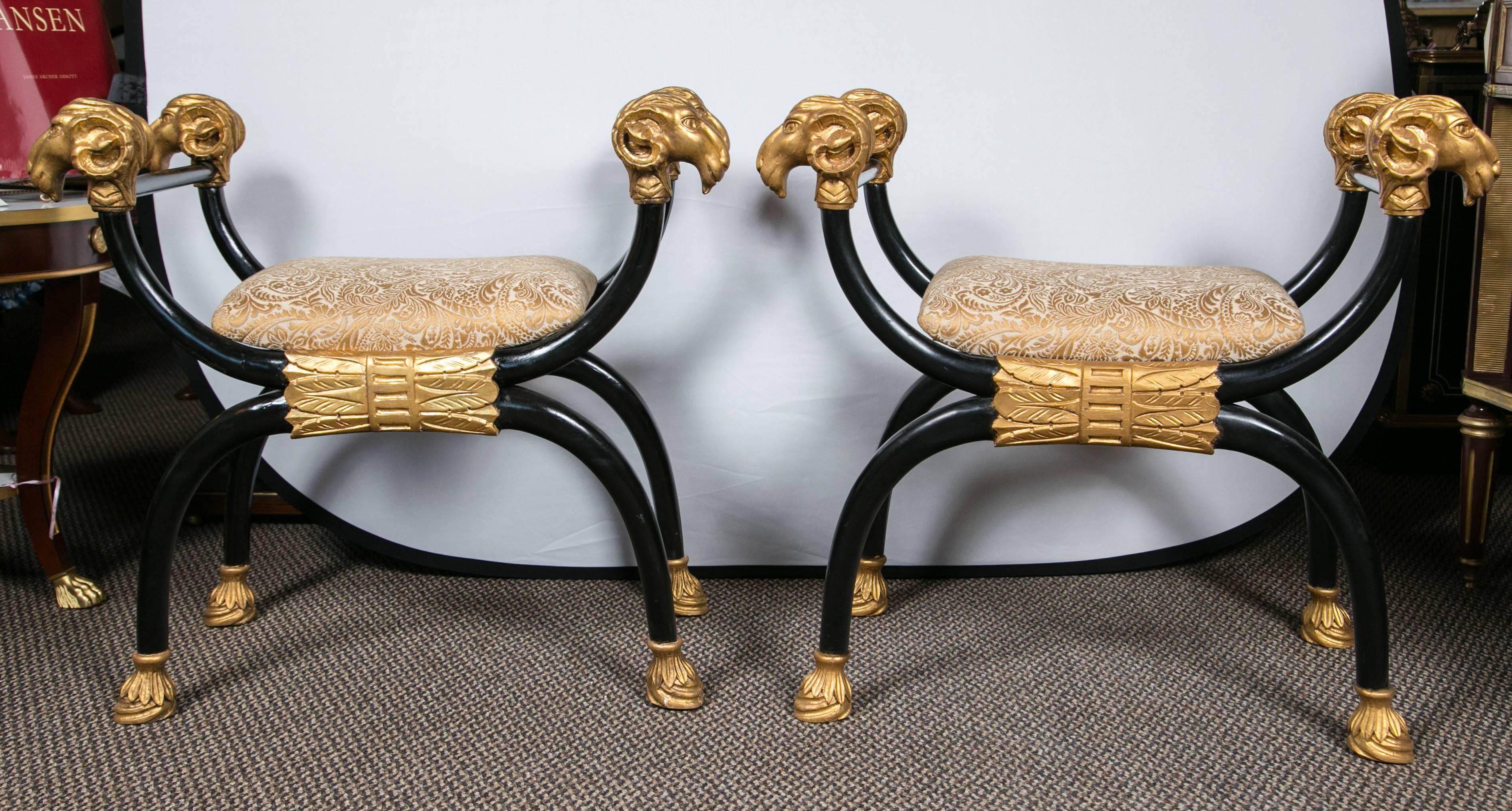 Pair of French Directoire style bench's, gilt gold and ebonized wood form. Decorated with parcel-gilt X-form styled rams' heads and ram's paws. The stunning 