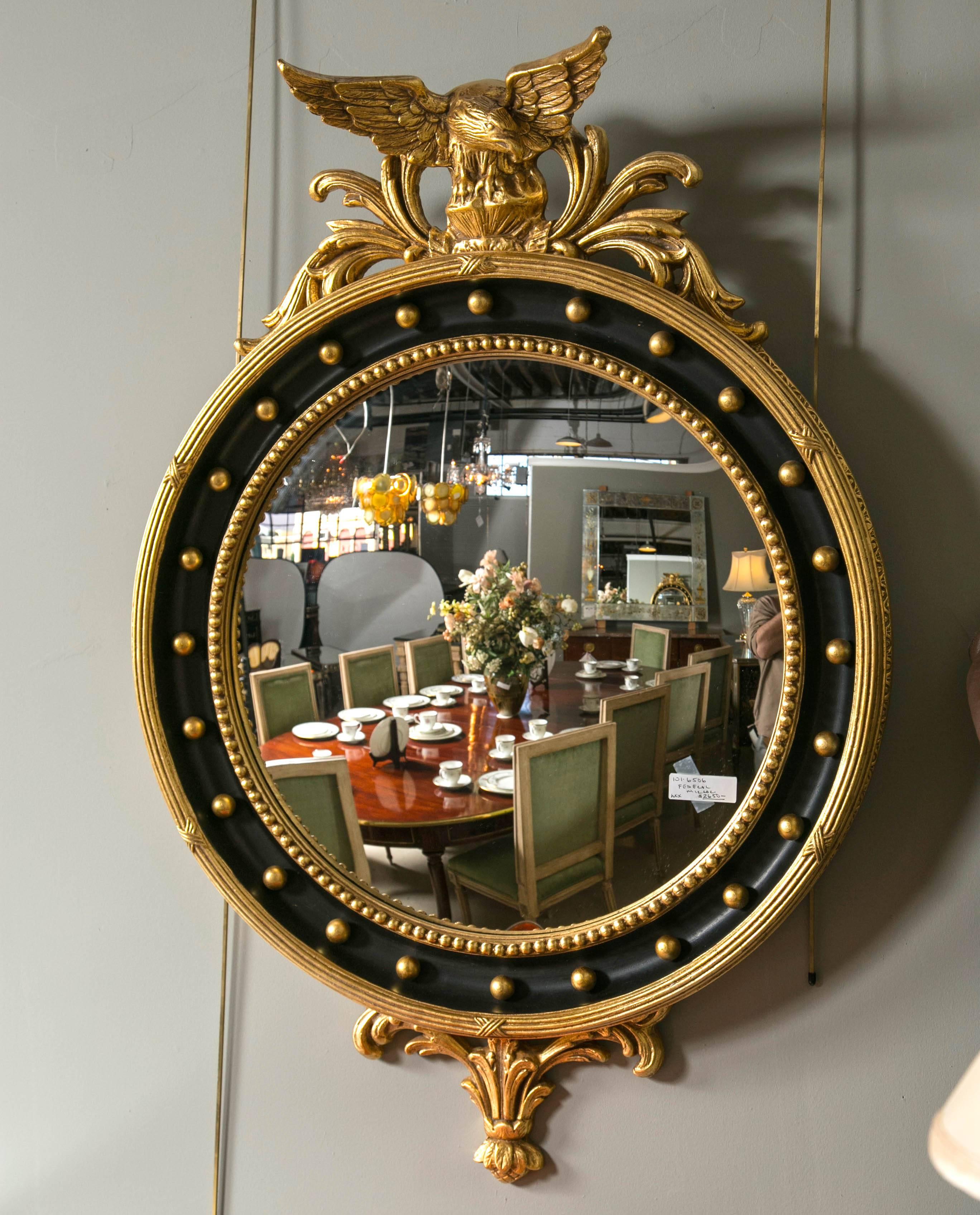 A custom quality bullseye mirror with a fabulous perched eagle crest. Fantastic design with bullseye encompassing the glass atop a black circular quality wood with gilt framing depicting X design. The crest is an eagle landing on a rock. The detail