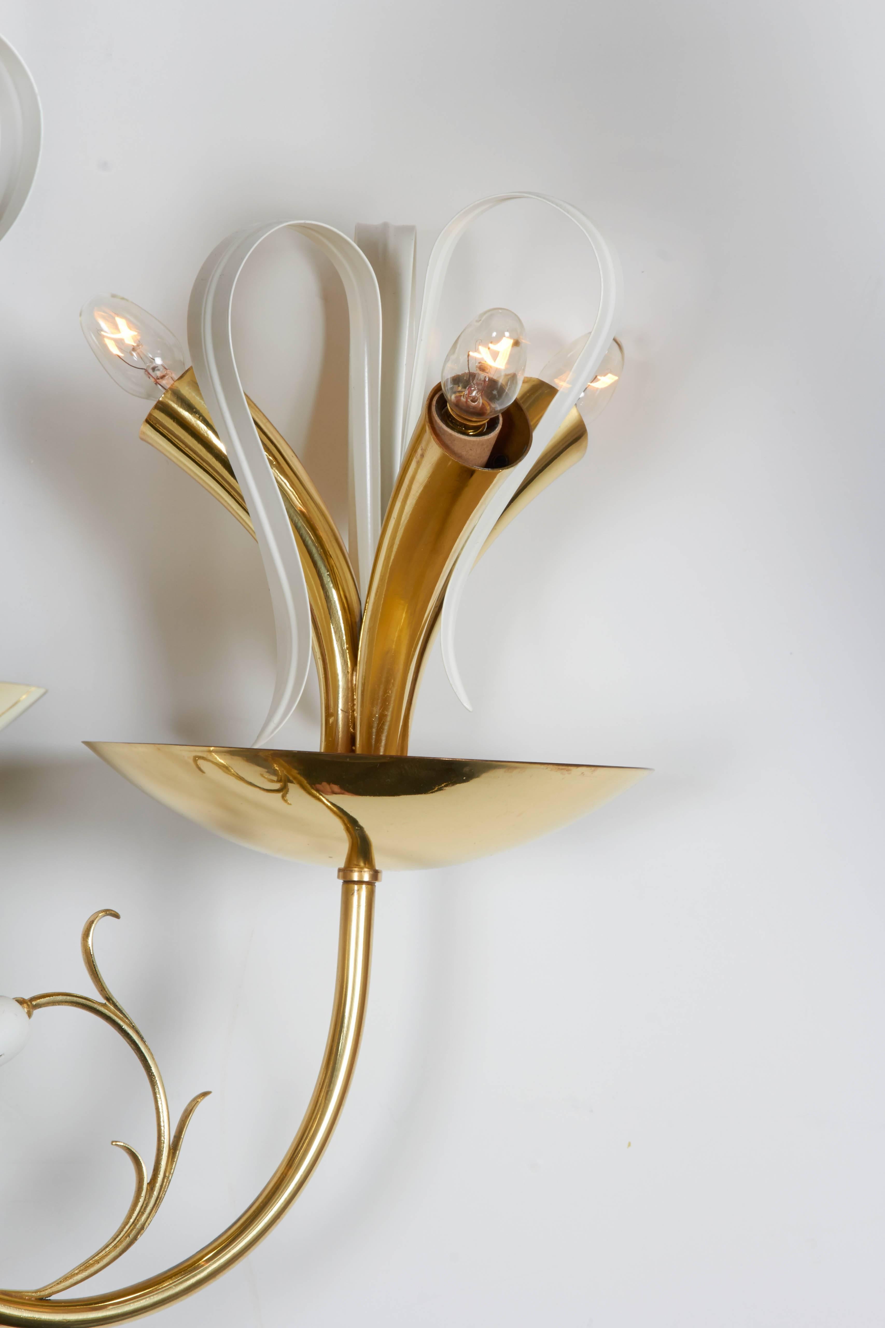 A marvelous, cheerful and optimistic example of post war mid-1940s to early 1950s lighting design. The body of the chandelier is made in brass with white enamel metal flower bud and leaf accents. Each arm supports a dish with three curved cone