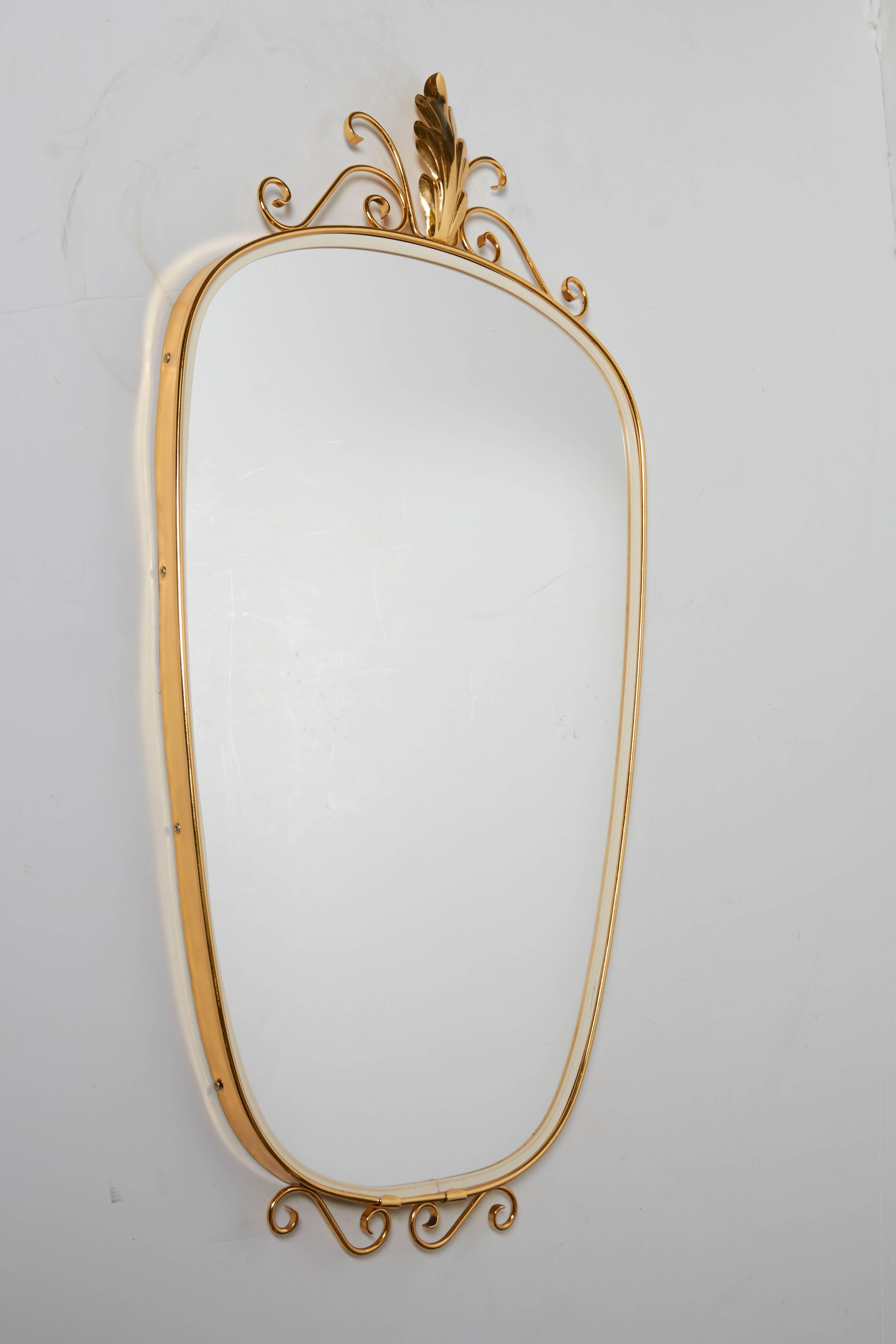 Italian 1950s oblong brass mirror with top acanthus leaf and scroll ornament and bottom scroll accents. Mirror has white rubber border inside brass frame. Measures 14.5" wide and 28.25" high. Brass newly polished and lacquered. Located in