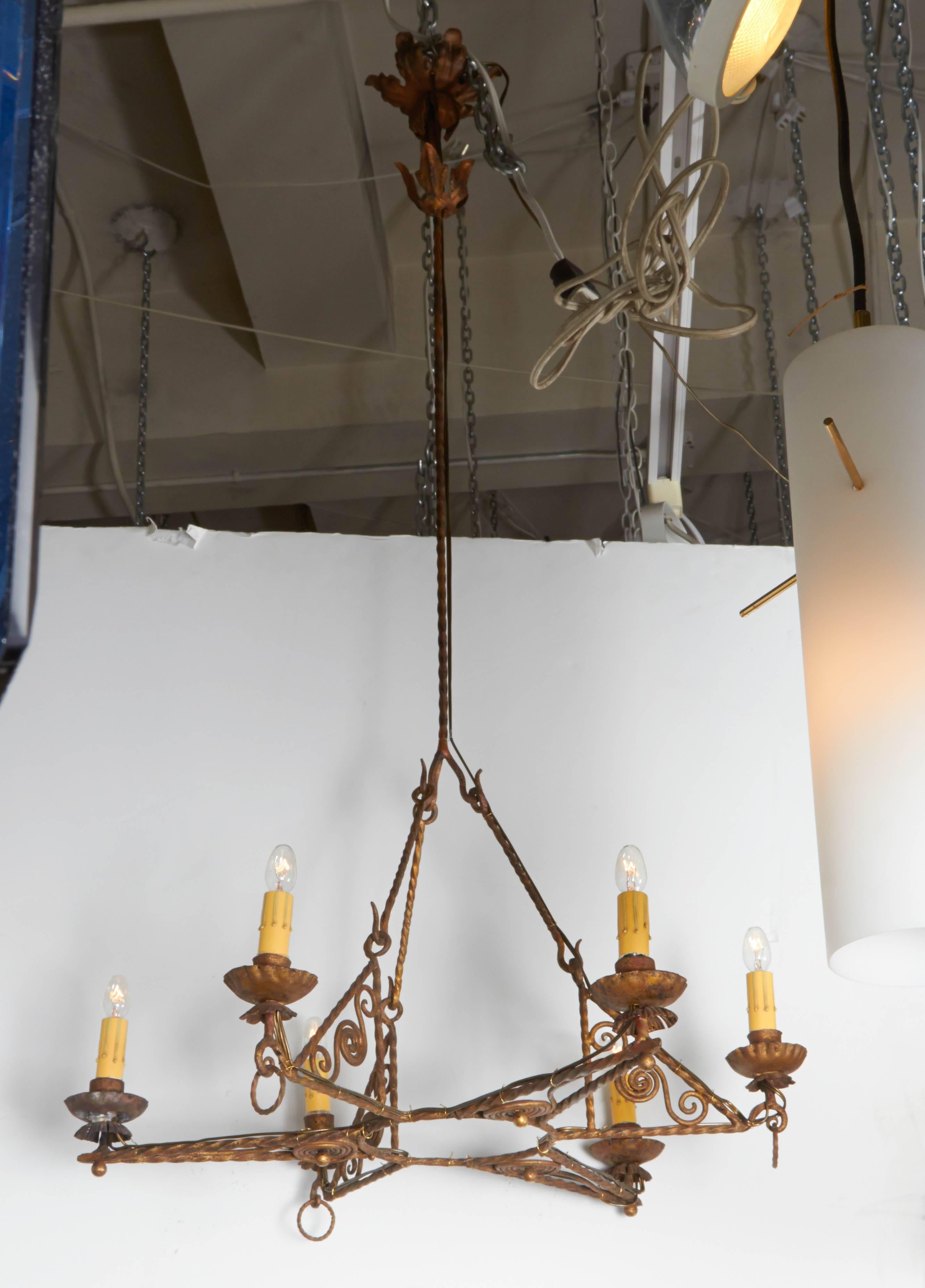 A very nice Italian Art Deco chandelier, circa 1920. Entirely hand-wrought and gilt iron with spiral scroll work accents. Six arms support each candelabra socket with cover in a star design. Externally re-wired in the same manner as found in an