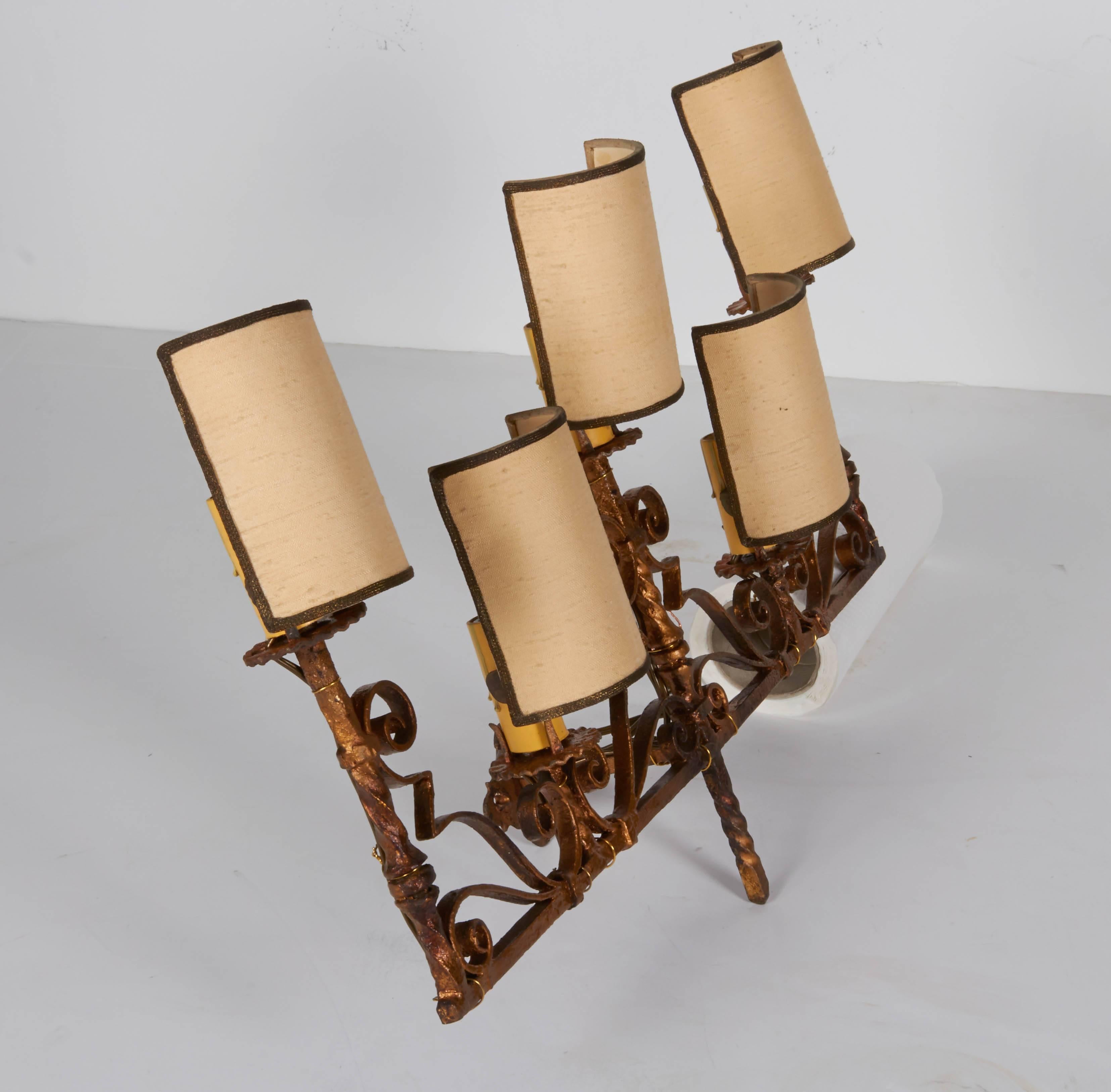 A wonderful pair of Italian 1920s gilt iron sconces. Each sconce holds five candelabra bulbs and comes with on shades. Shades are circa 1950 and attached to sconces when found. Each sconce measures 19.5