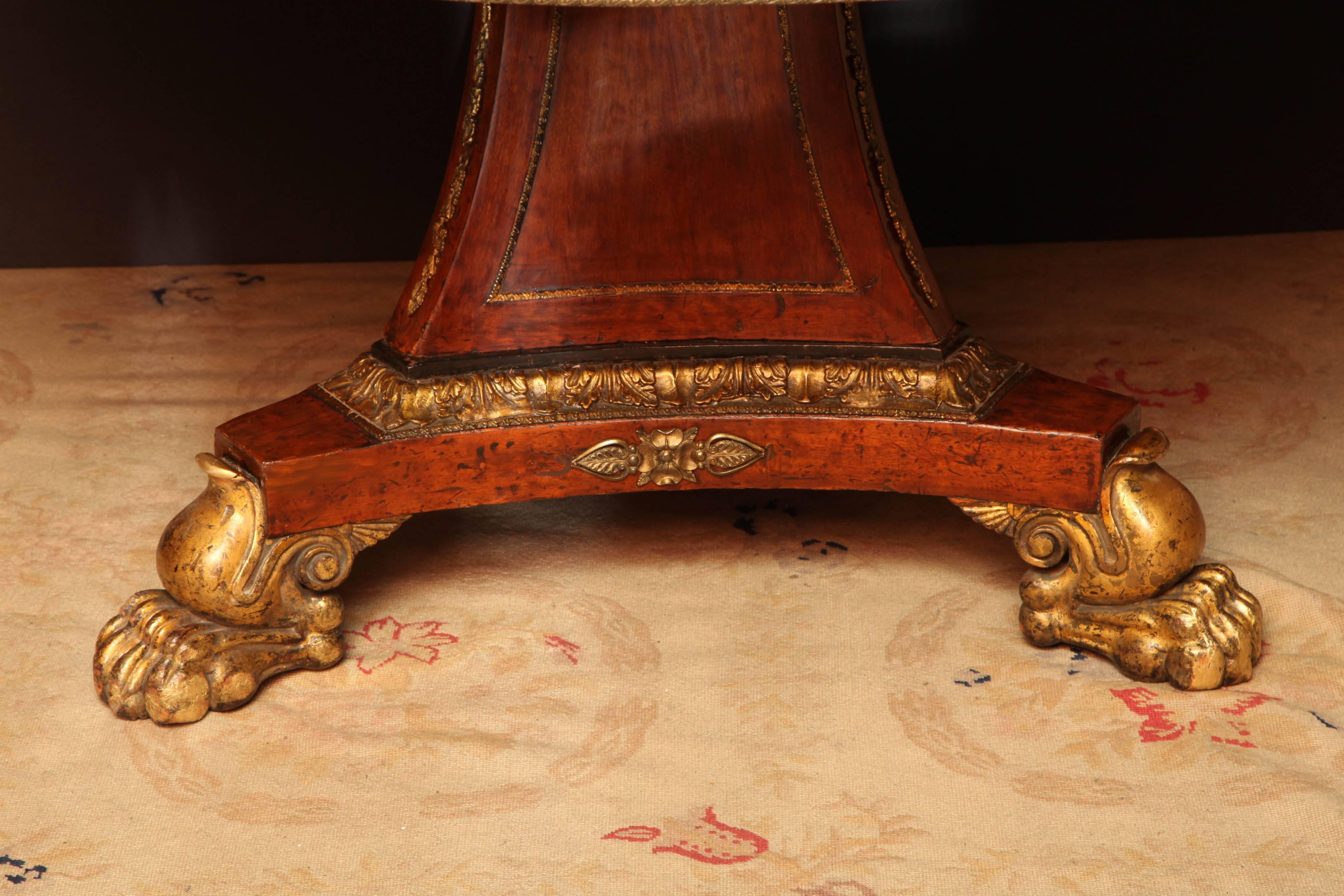 Regency mahogany tilt-top centre table with calamander wood and brass banded edge on an incurved tripartite base with robust gilt paw feet.
