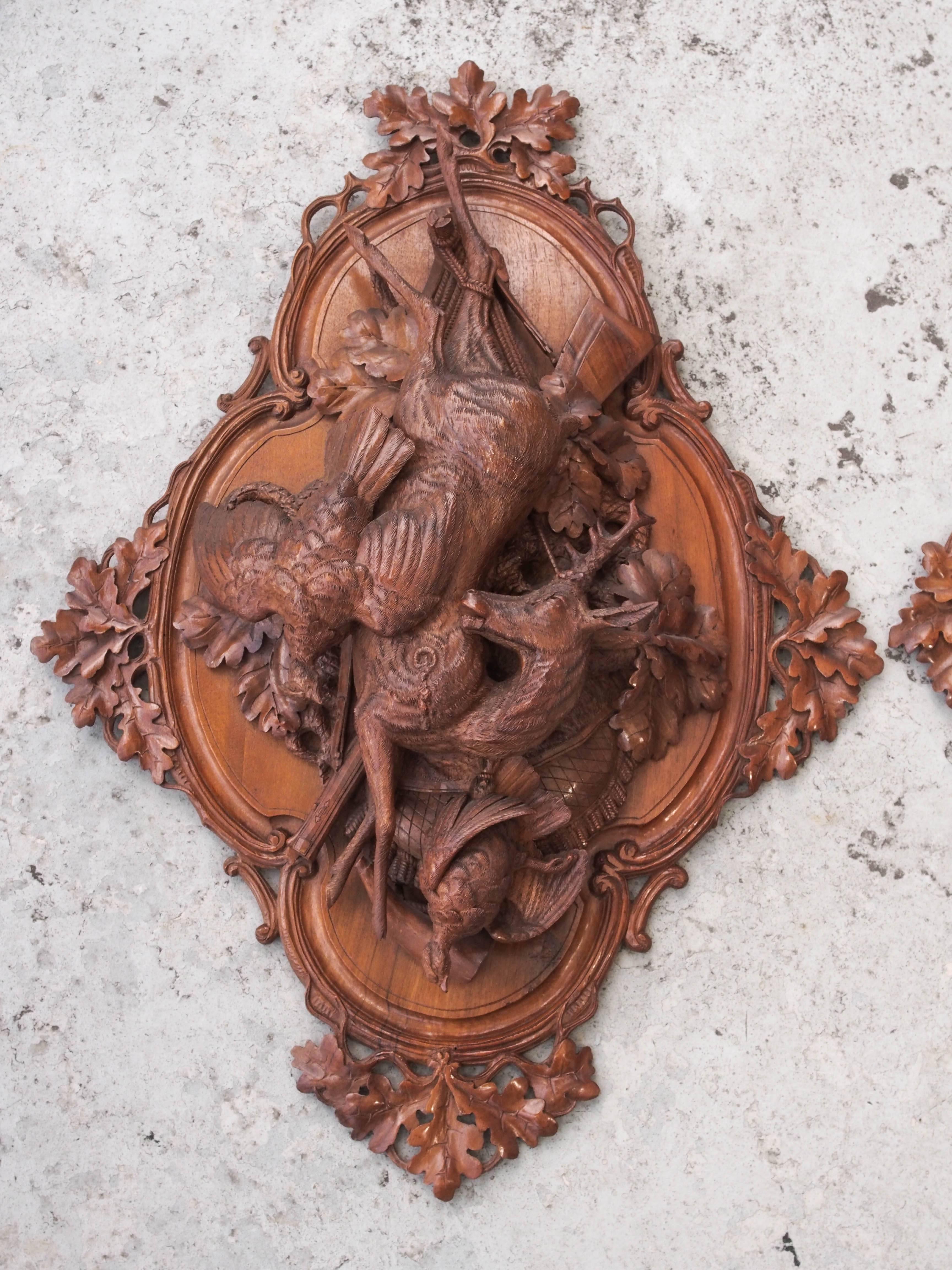 Pair of Black Forest carved wood wall plaques of game of the hunt.