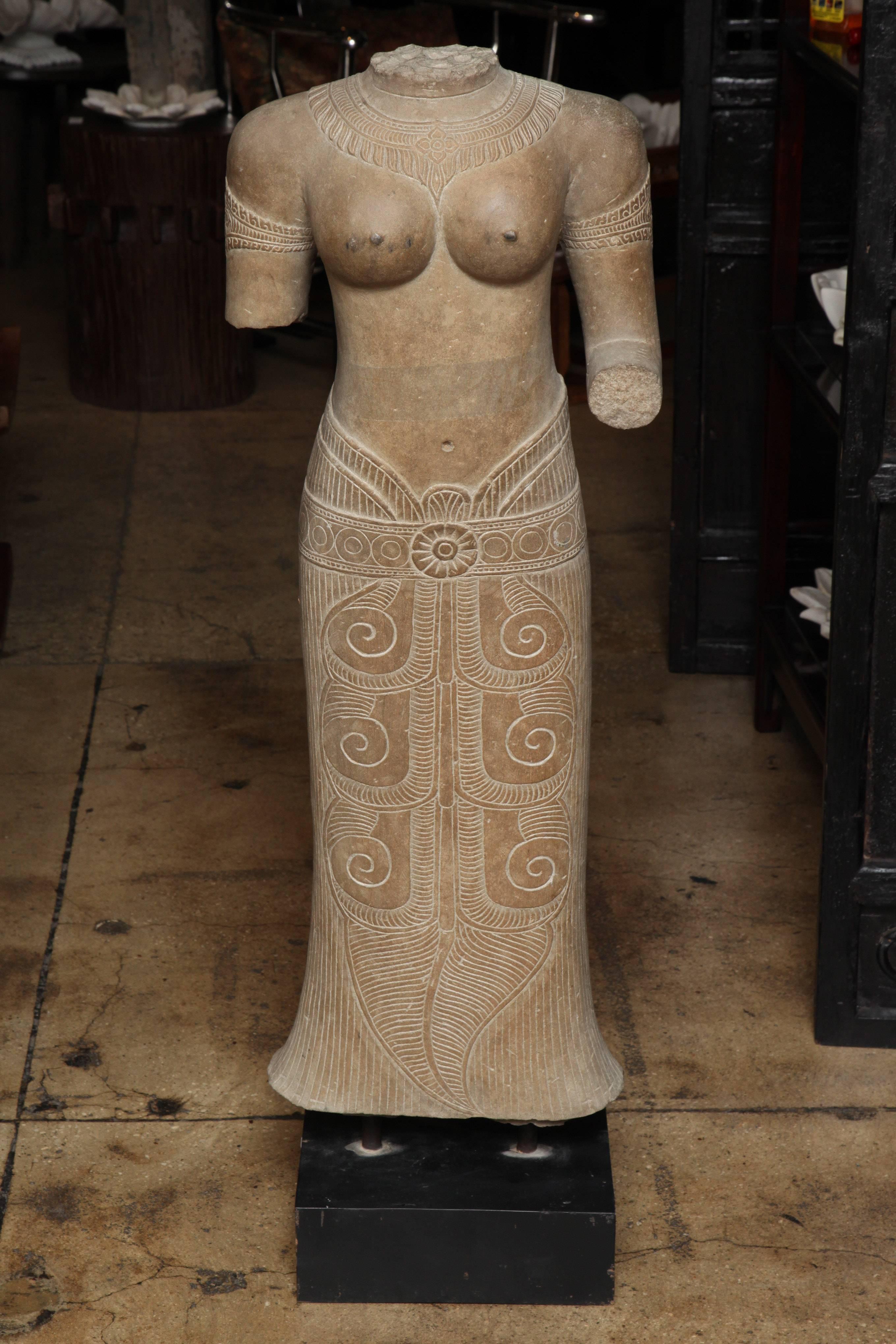 A carved stone female torso, from Thailand, on a stand.