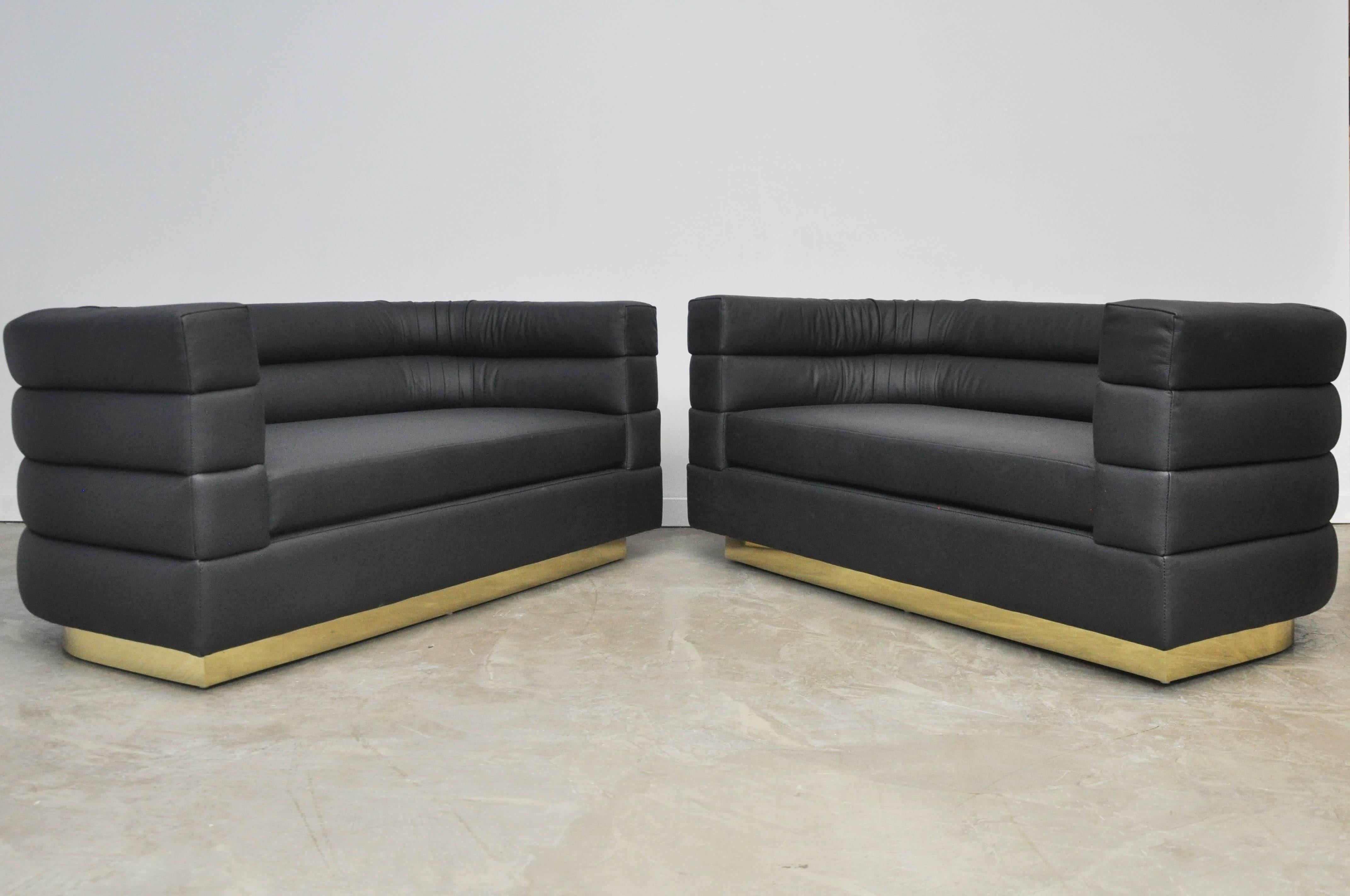 Pair of black leather settees on brass bases by Design Studio, circa 1970. New leather upholstery.