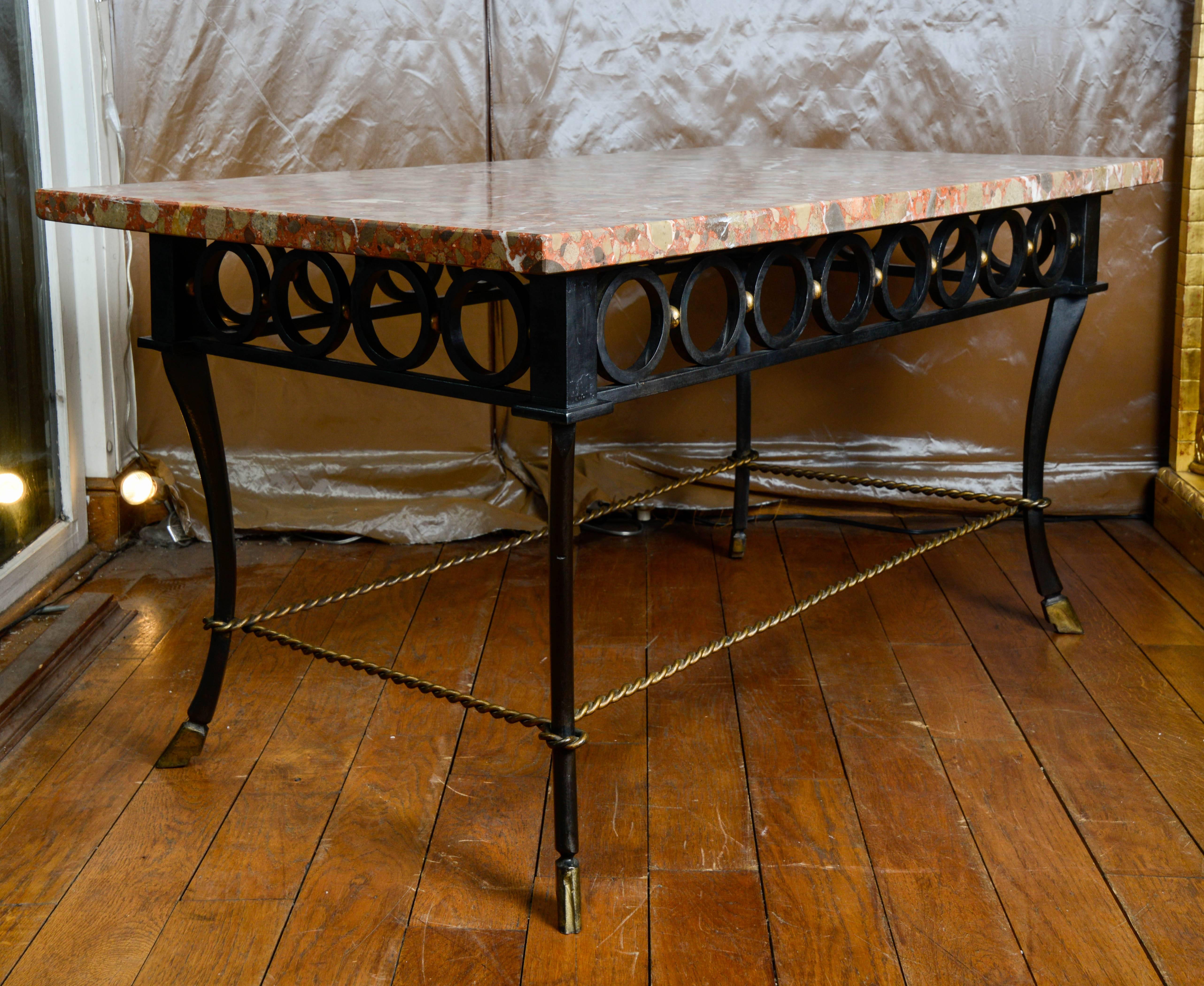 Table designed by Gilbert Poillerat composed of a marble panel with warm tones and a part of wrought iron, heart of the work of Gilbert Poillerat. The base of the marble panel is a frieze around 13cm high, made in the length of eight circles, and in