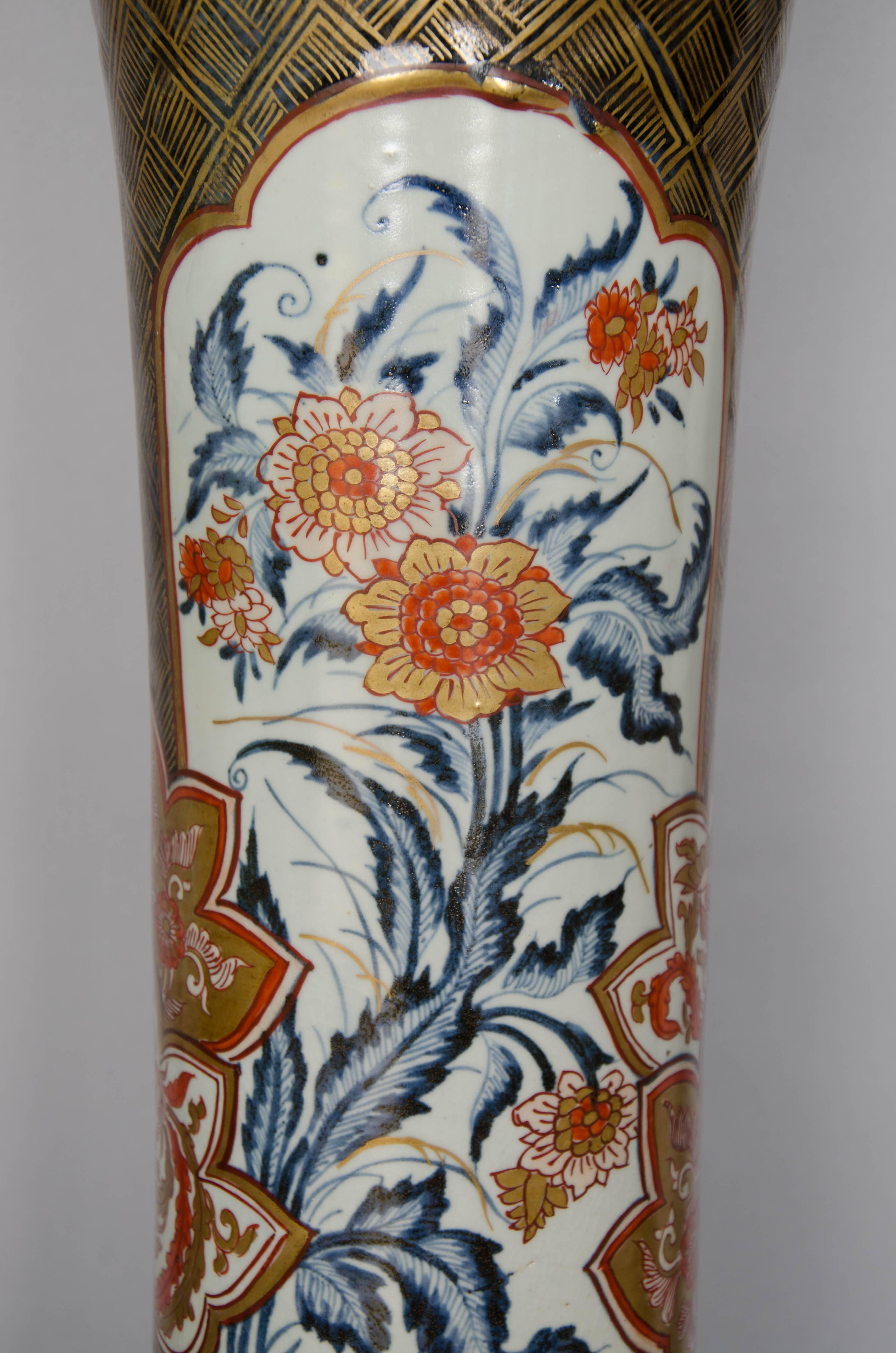 An impressive pair of trumpet-shaped Japanese Imari vases each one decorated with two white panels of underglaze blue scrolling flowers on a dark blue and gold background.
Conditions: One is perfect, the other has a couple of hairline cracks