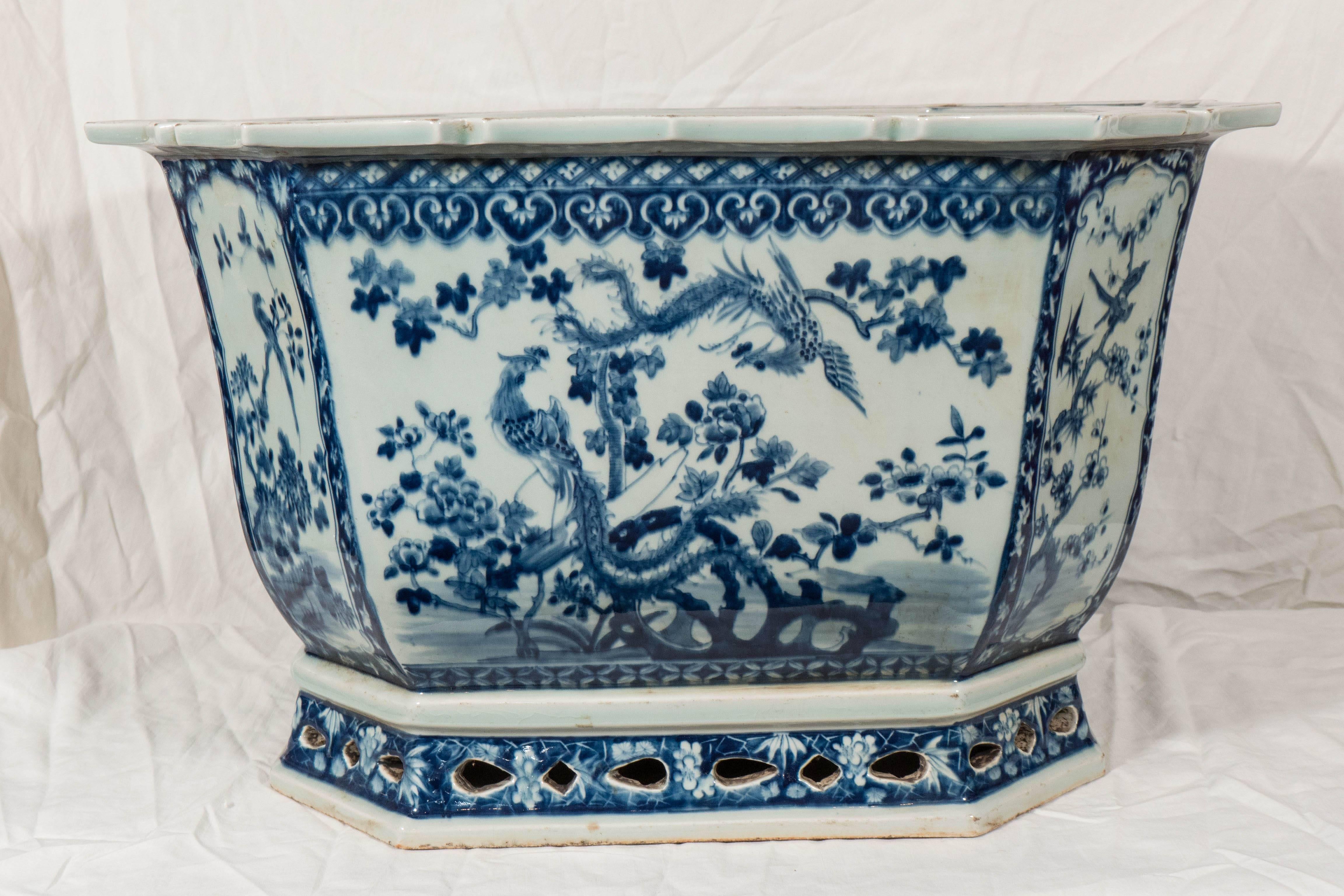 A large Chinese porcelain jardiniere painted with a floral motif in underglaze blue and white. Beautifully decorated with hand-painted panels on the front and back showing long tailed birds in a garden of flowering peonies. This cache pot has two