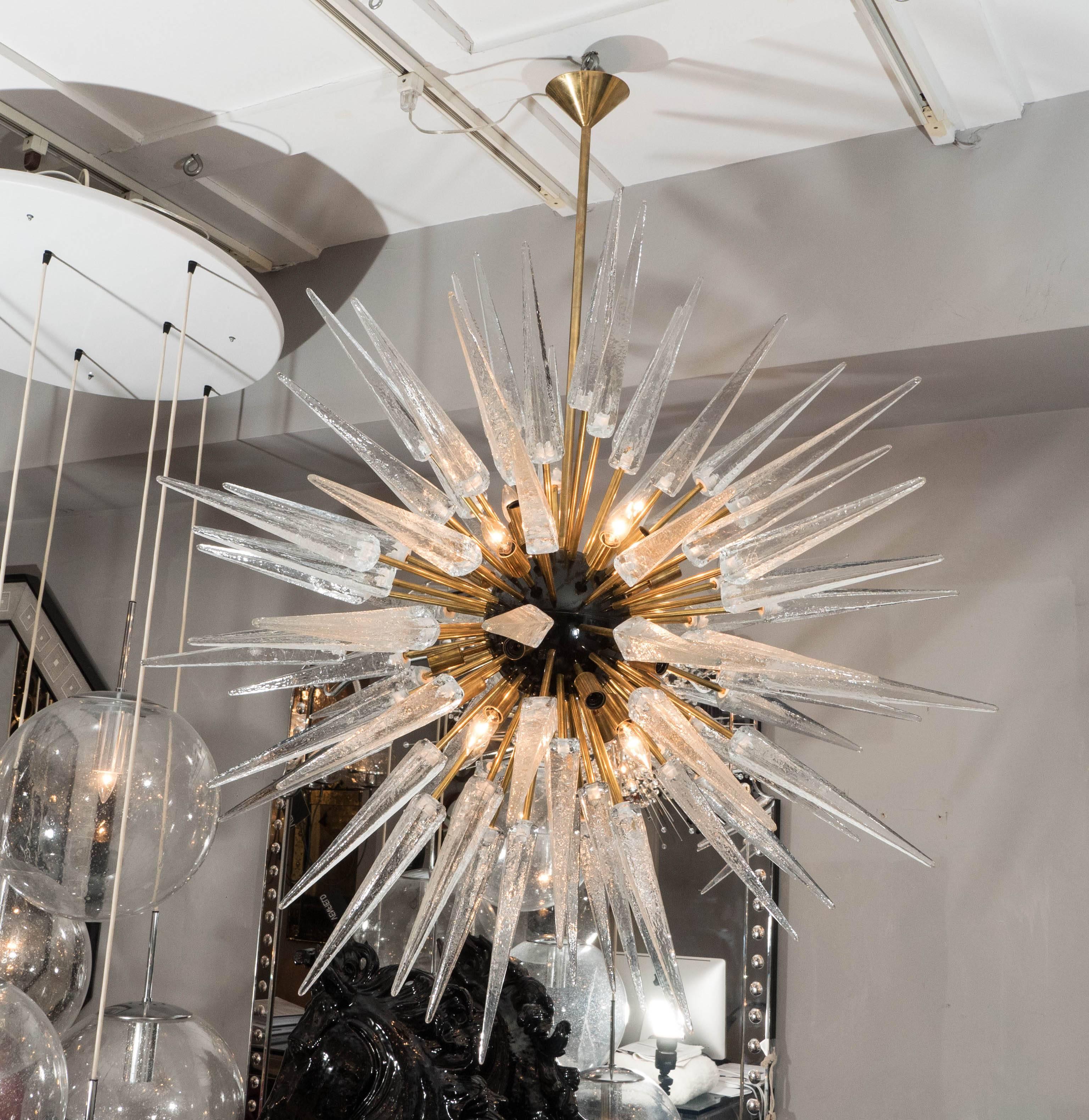 Lampadario Sputnik a punte in vetro di Murano trasparente con sfera centrale nera e struttura in ottone non laccato. La personalizzazione è disponibile in diverse dimensioni, finiture e colori del vetro.