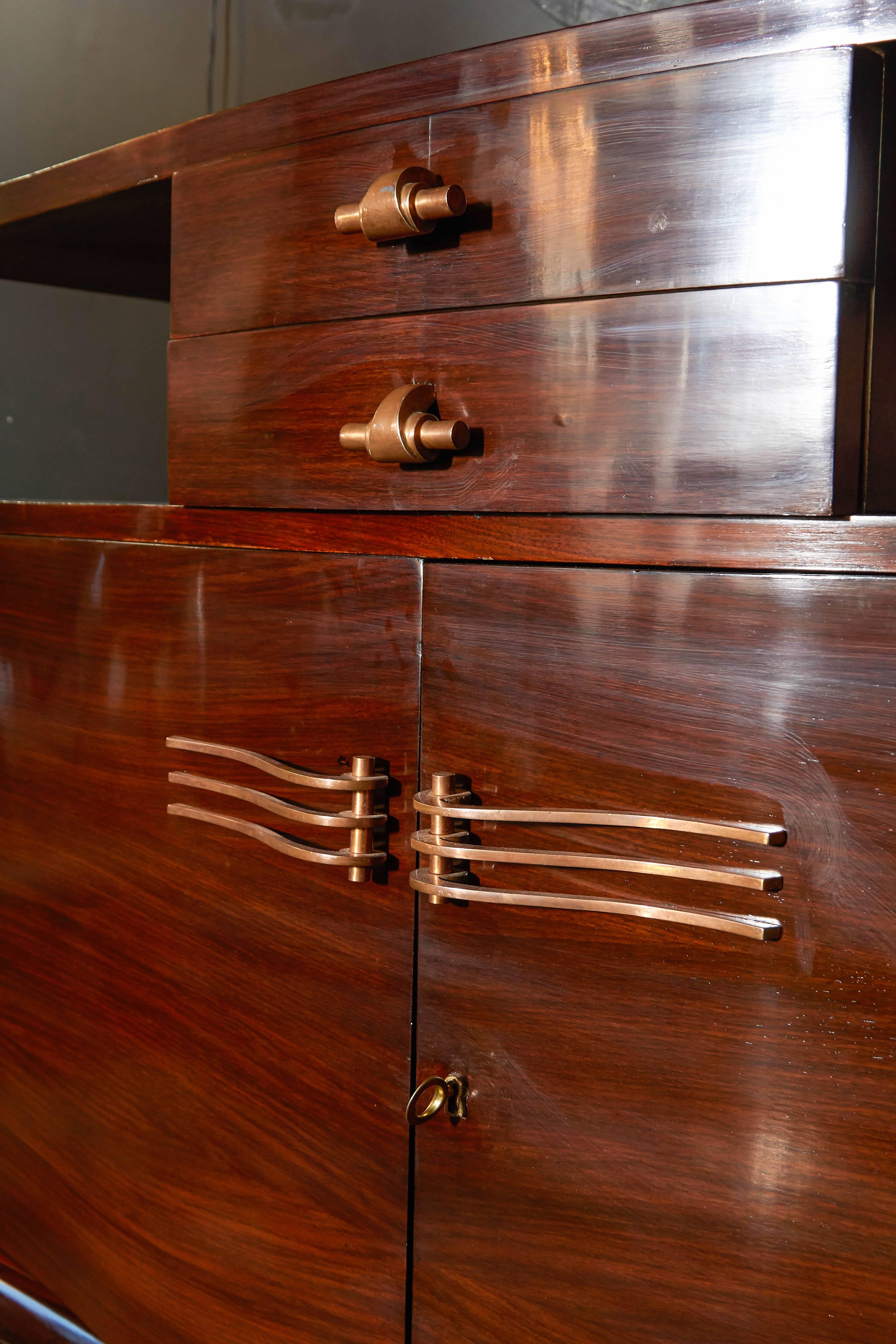 Exquisite Art Deco sideboard comprised of bookmatched rosewood with a semi-gloss French polish. The sideboard features elegant bow fronts with slightly scrolled or arched cabinet doors. Fitted with two top center drawers, as well as open cabinet