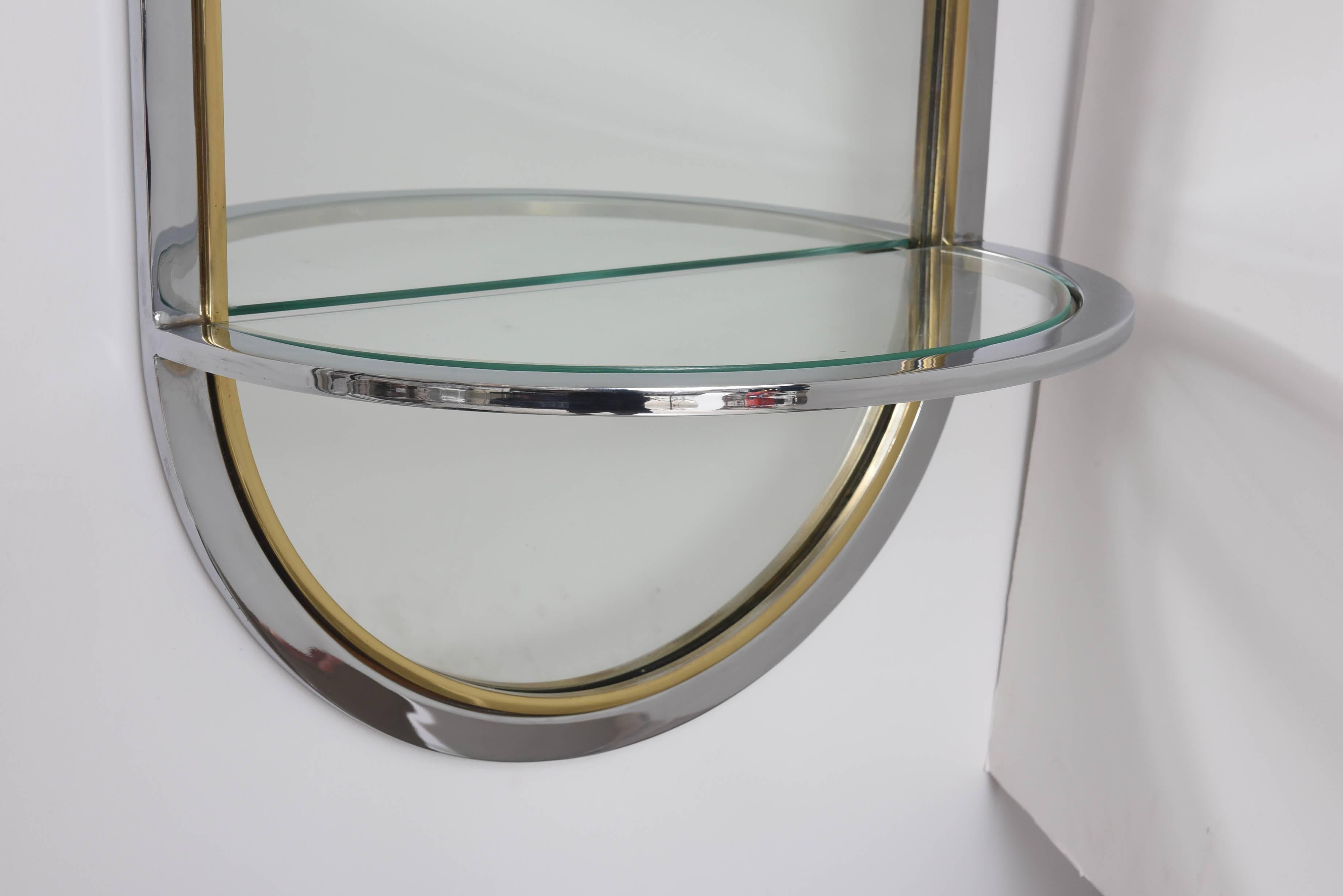 This piece was designed for DIA in the 1970s. The race-track design is comprised of a single band of polished chrome and a band of polished brass. The suspended shelf has an inset piece of clear glass.

Note: The shelf is 9.75