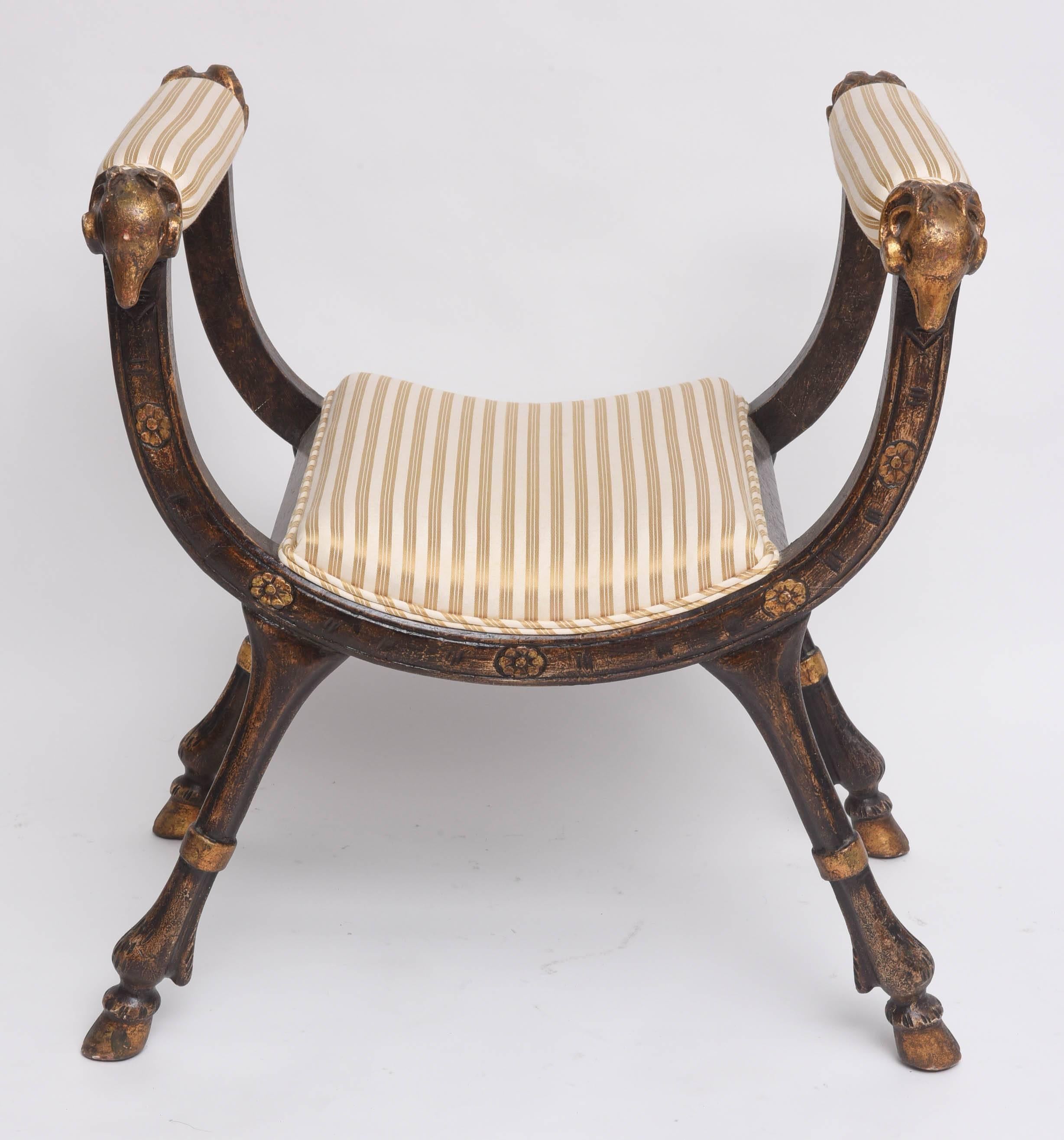 This amazing Neo-Classical style curule bench was acquired from a prominent Palm Beach estate.  The piece was definitely carved by a master-craftsman with its stylized rams-heads and hoofed-legs.  The piece retains its original painted and