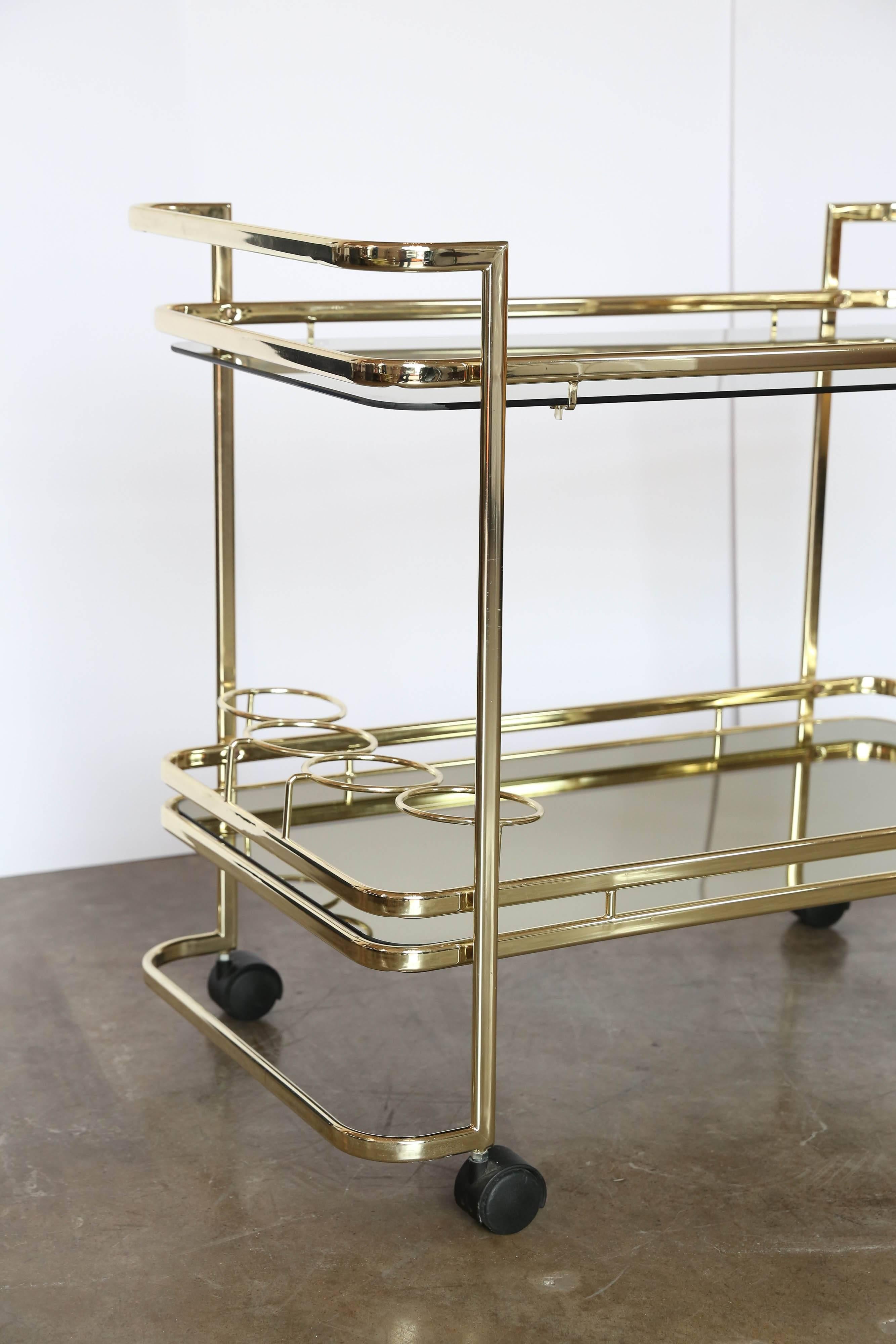 Offered is a high glam bar or tea and service cart with a glass top shelf, mirror bottom shelf, gold tone metal frame with a built-in area for bottles. This piece would be perfect for entertaining or just displaying a fabulous bar on wheels.