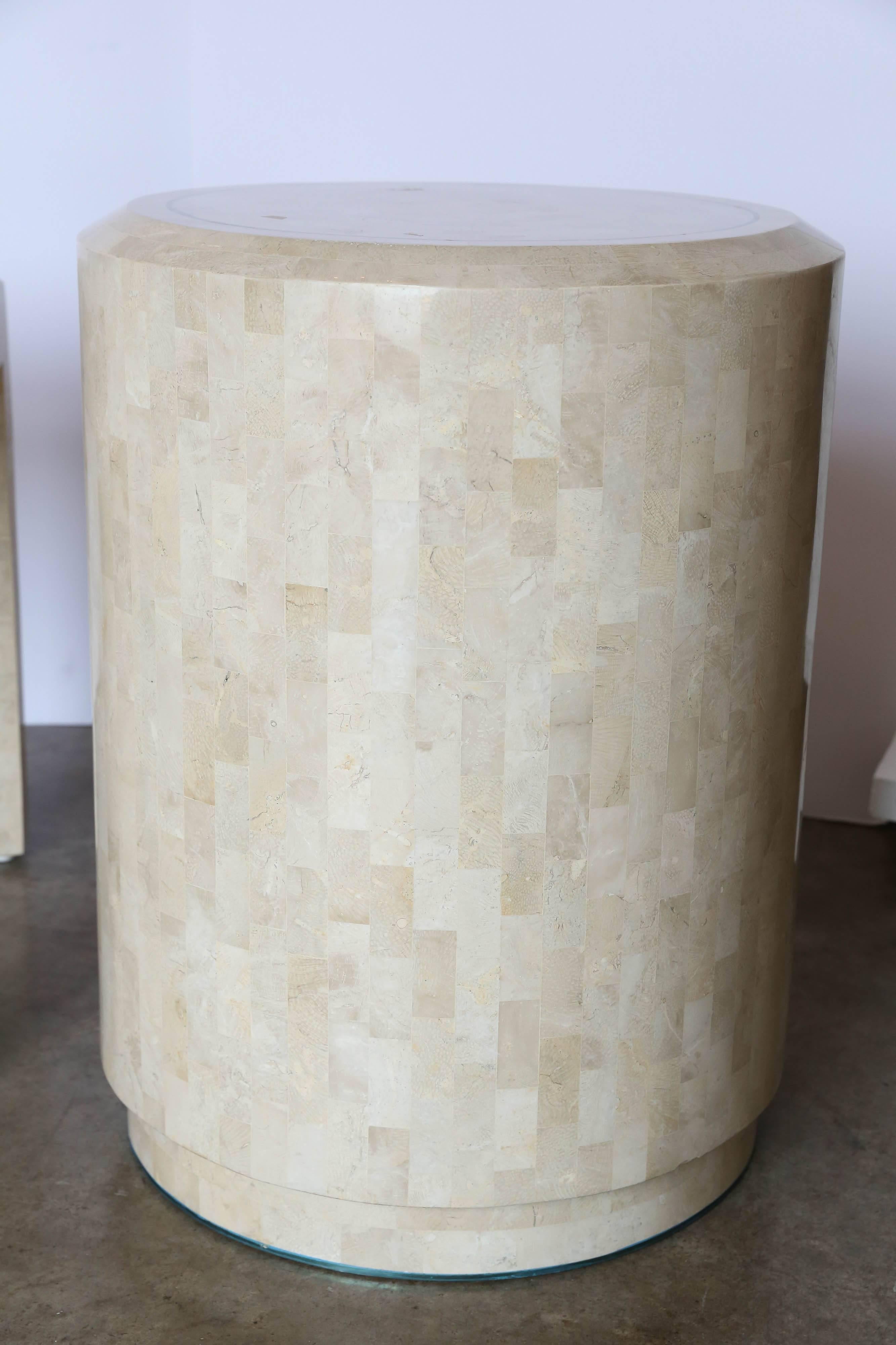Offered are two side or end tables of ivory and tan tessellated fossilized coral with inlaid brass by Maitland-Smith. One table is circular and the other rectangular. The dimensions for the rectangular side table is: 27.0