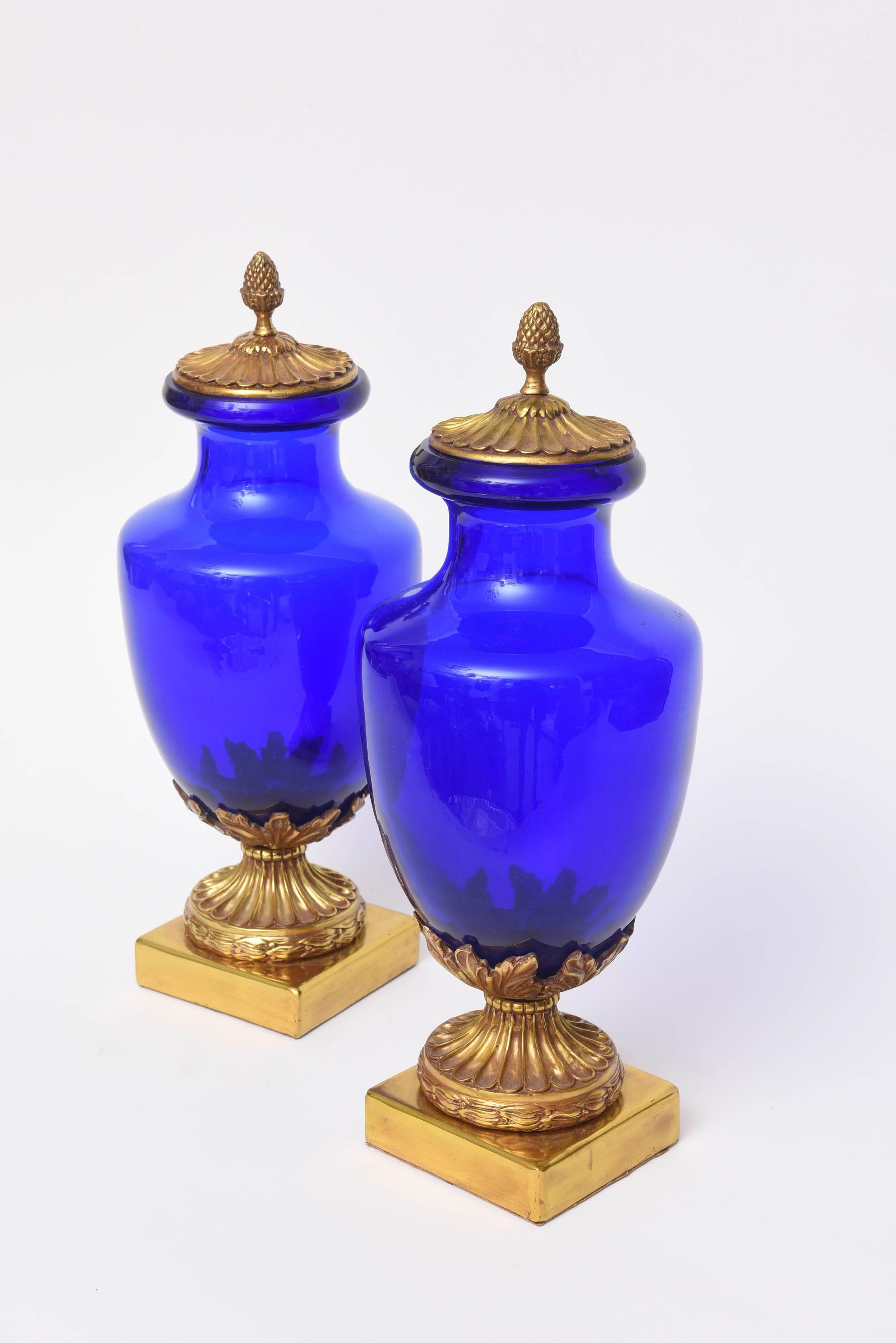 Beautiful pair of cobalt blue glass urns with bronze bases and lids.