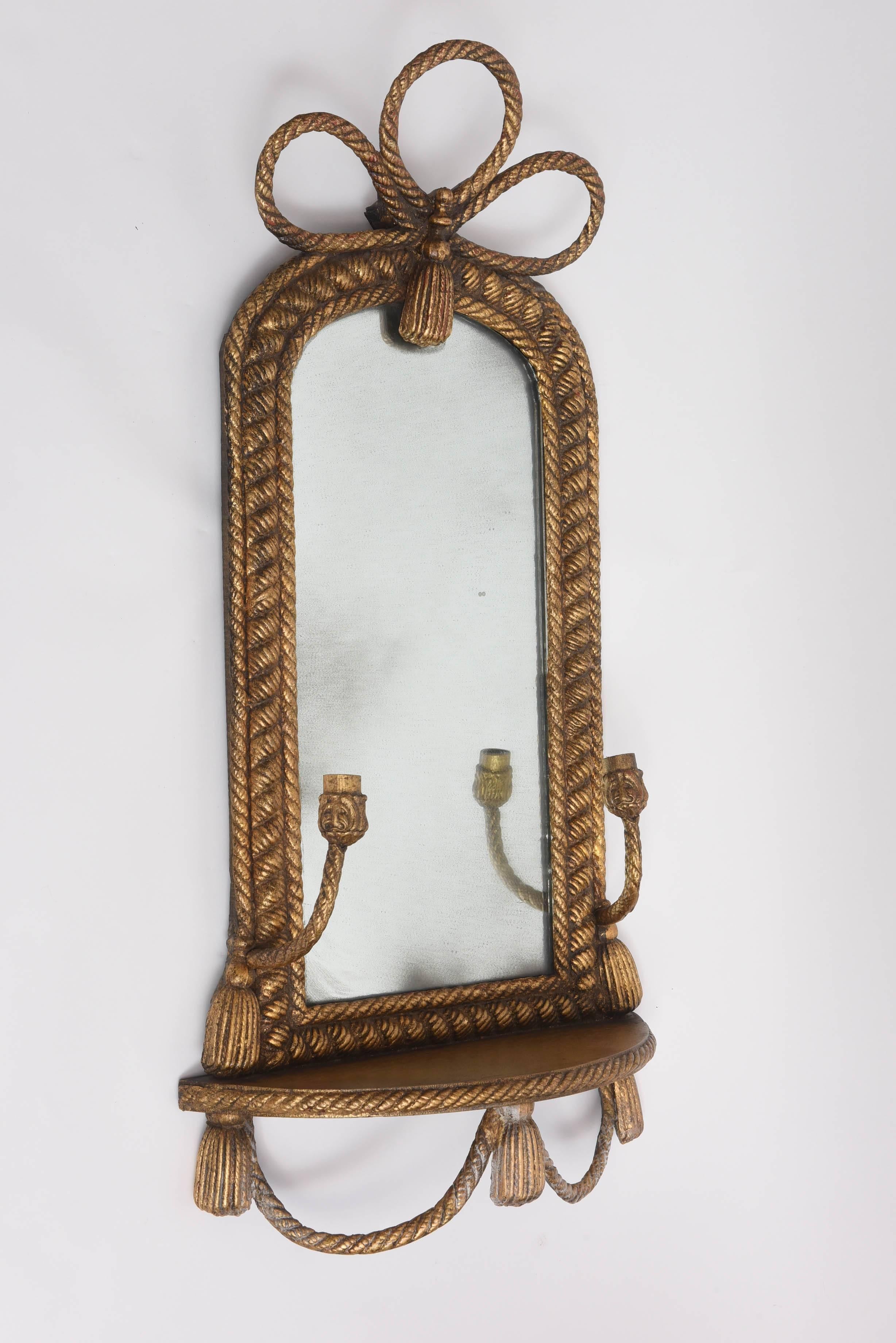 Interesting pair of wall hanging mirrors with shelves and candle holders. Graced by a rope and tasseled motif.