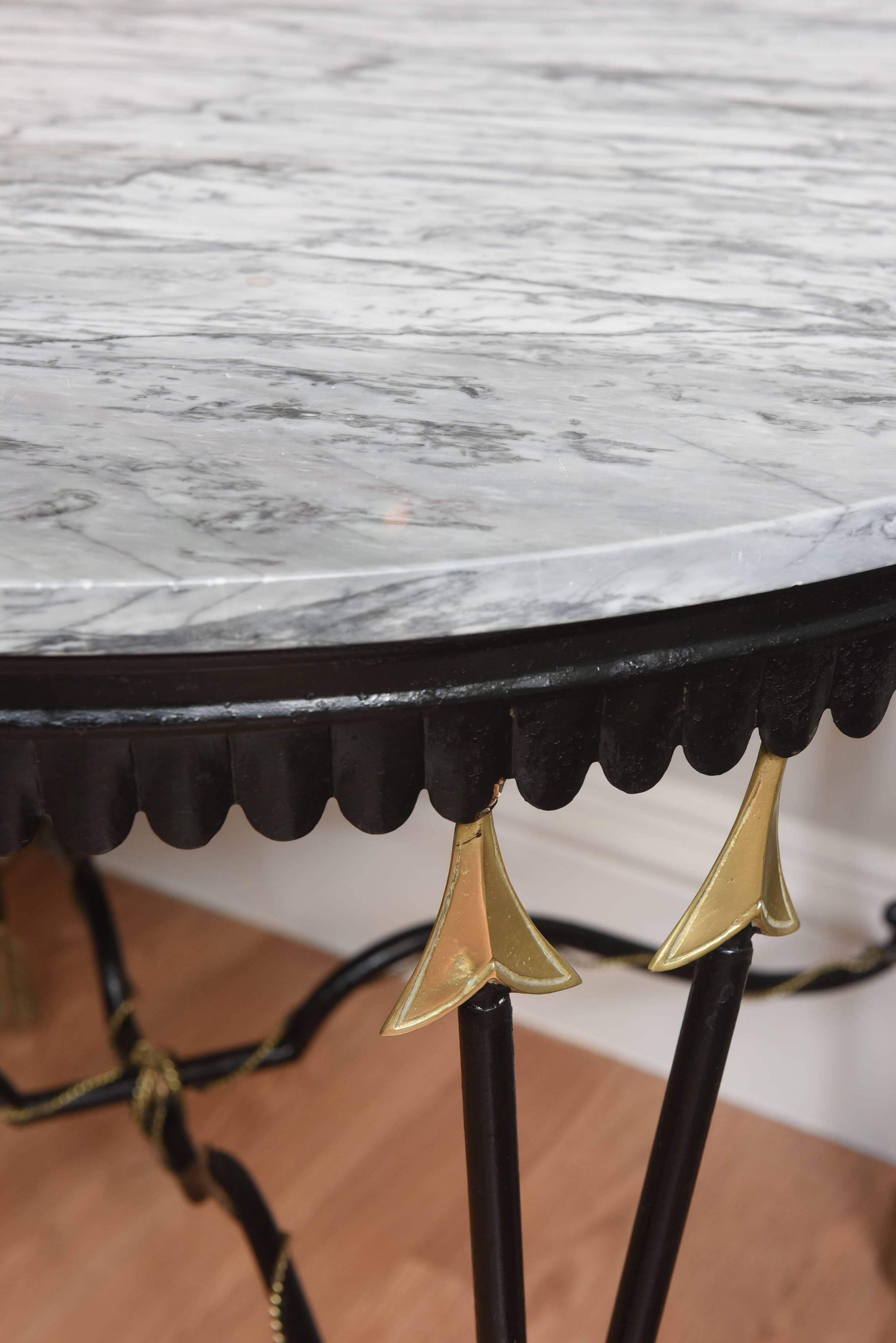 Stunning wrought iron and brass neoclassical center table with crossed arrow legs. Finished with gilded arrow heads and feathers. Original marble top.