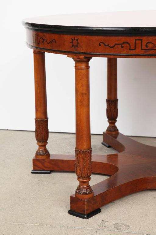 A Swedish grace birchwood and ebonized inlay side table, circa 1930s, the radiating birch veneer top with an ebonized molded edge, the frieze with ebonized inlays raised on six column supports with carved leaf banding ending with a six sided concave