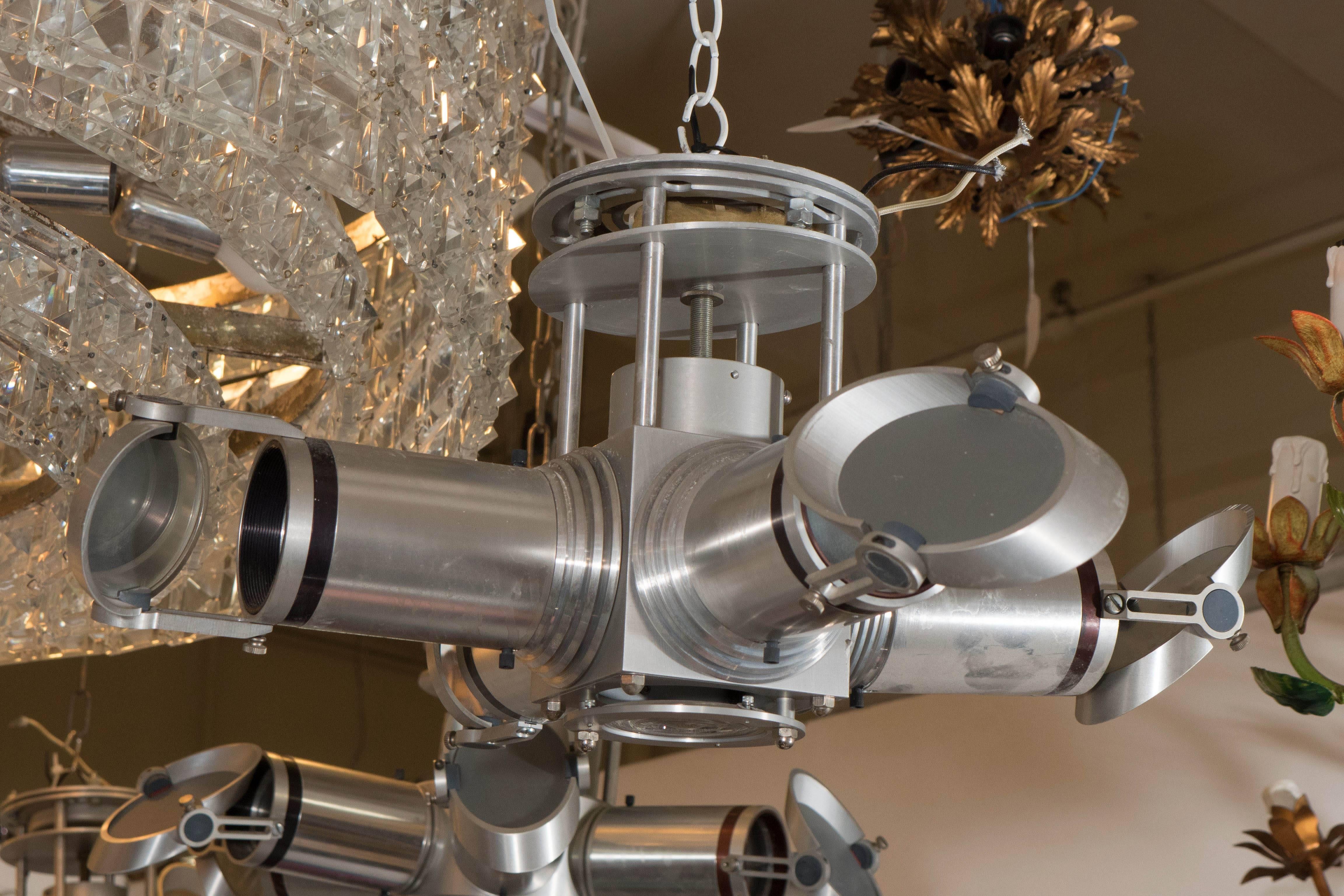 A unique Space Age style light fixture in brushed chrome, with four tube shaped 'telescope' arms of varying lengths, each with adjustable mirrored lenses, to alter projection. Very good condition, consistent with age and use.