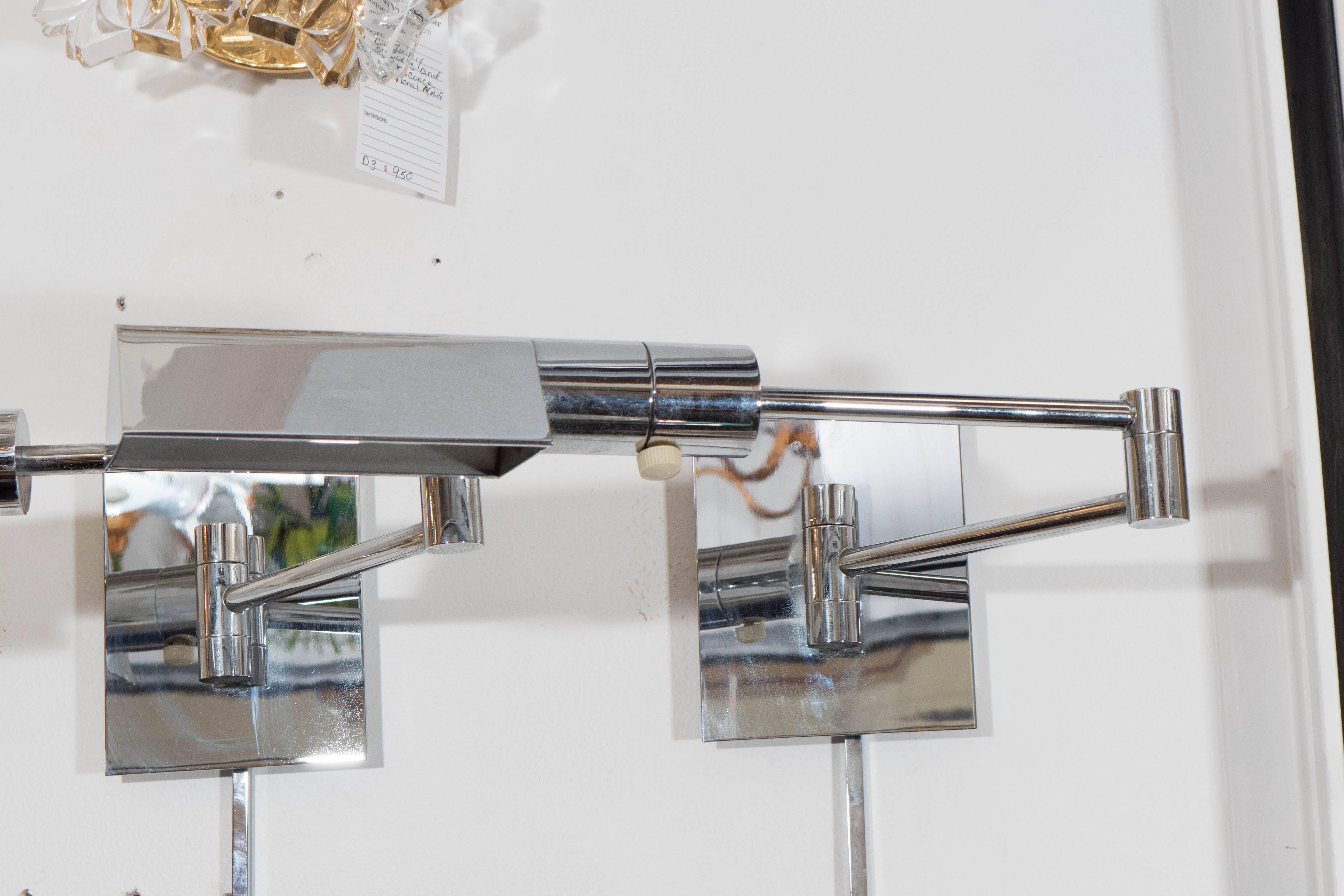 A pair of wall-mounted reading lights in chrome, produced by Casella circa 1970s, each with a geometrically designed triangular shade, supported by an articulated arm that can adjust and extend from the backplate; includes chrome strip, to cover the