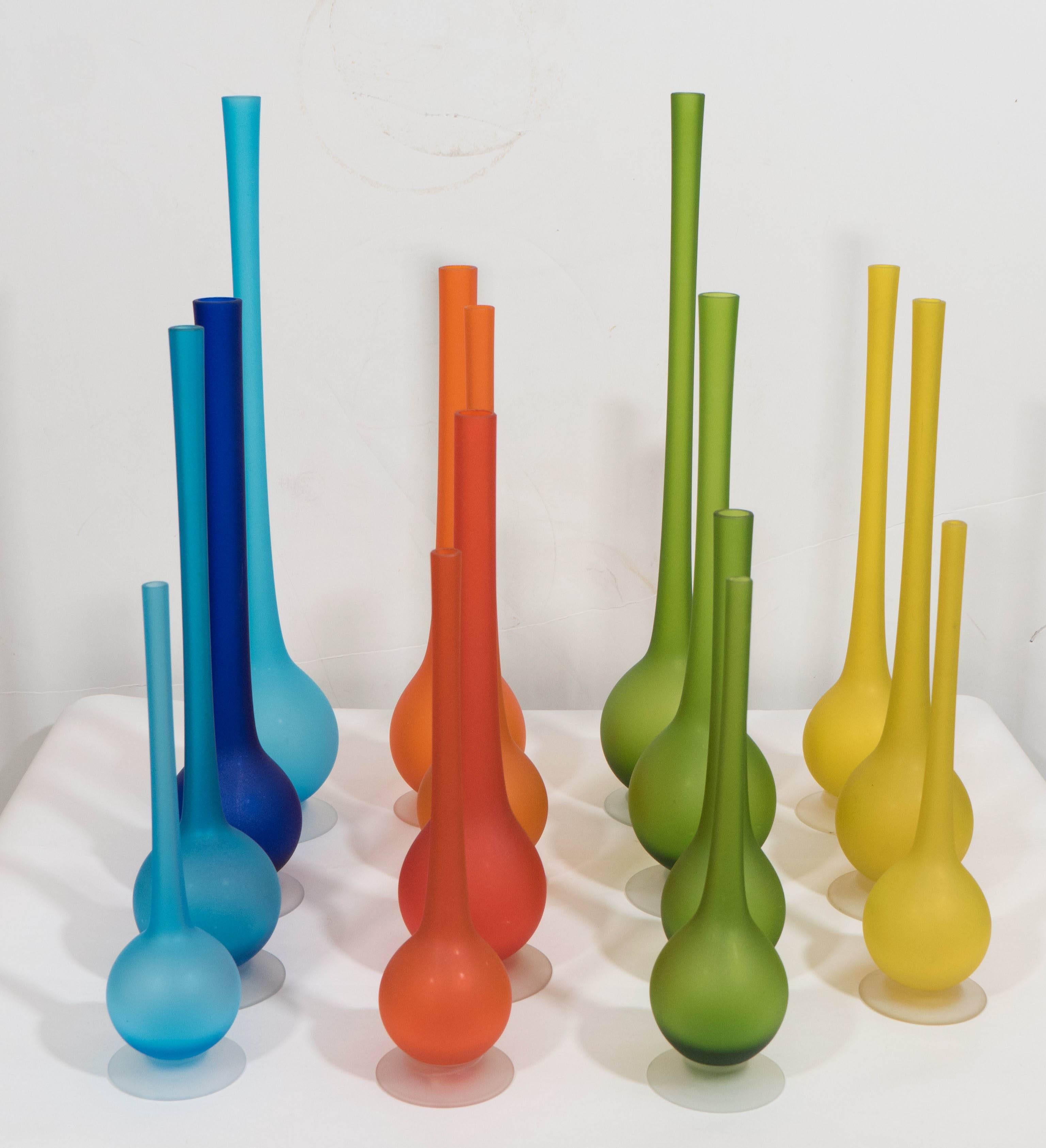 An arrangement of fifteen satin glass vases, in a variety of sizes and bright colors, created by Italian designer Carlo Moretti, circa 1970s, each with pencil necks over rounded bodies, on a single circular foot. Markings include sticker labels
