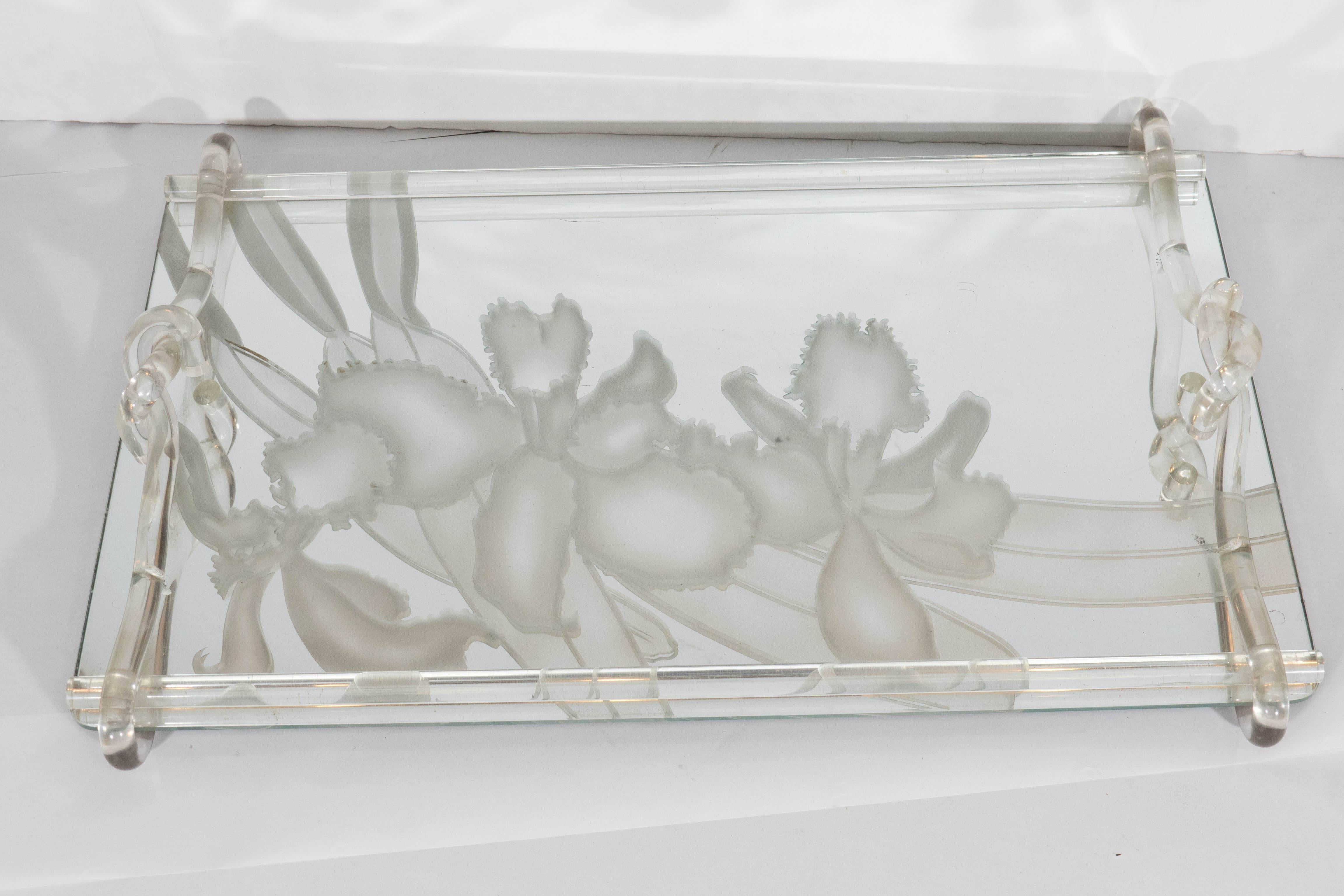 A vintage serving tray, produced sometime between the 1940s and 1950s by designer Dorothy Thorpe, with glass mirror tray, beautifully decorated with layered etchings of floral designs, inset within looped Lucite handles. This piece is in very good